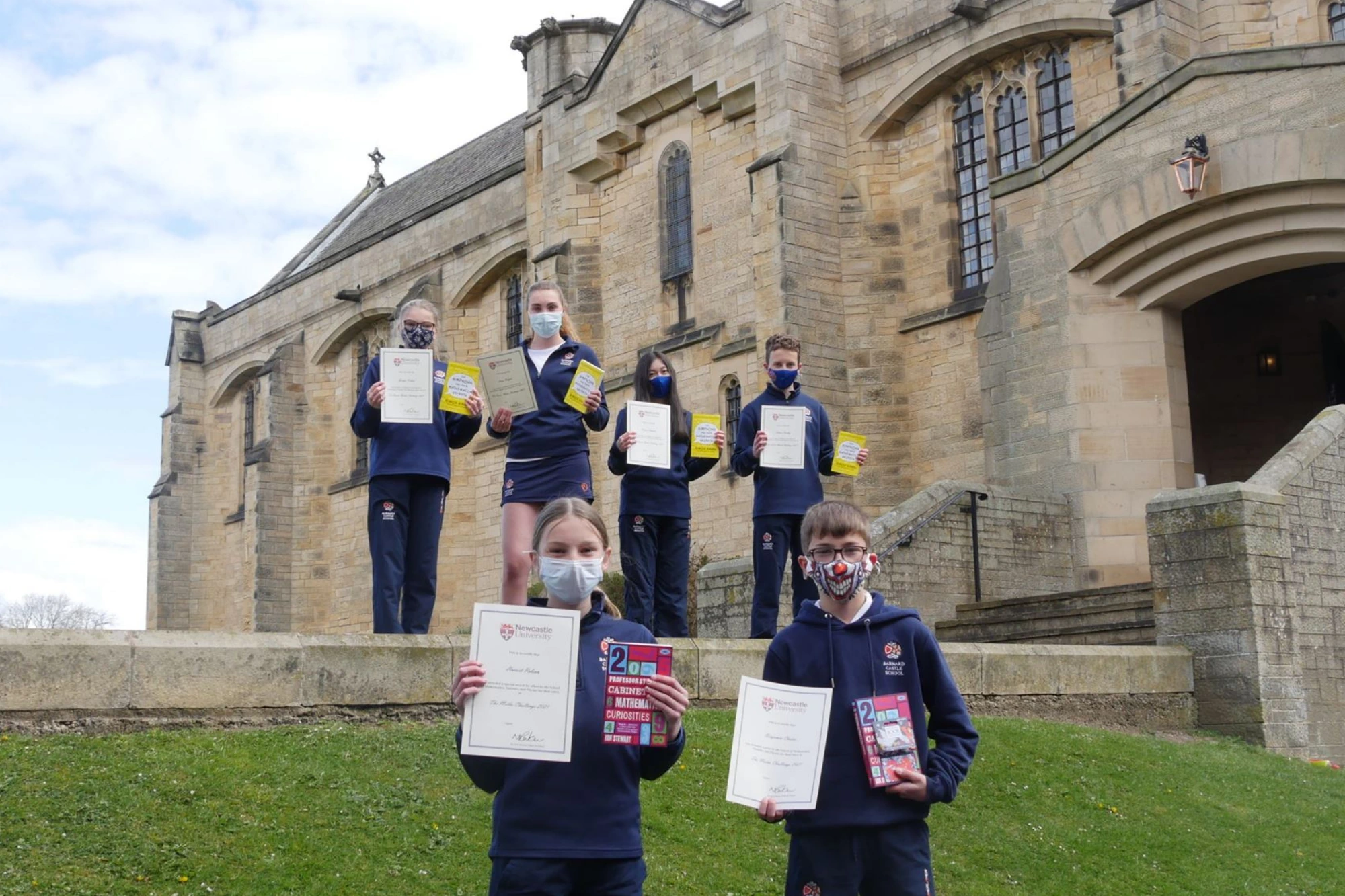 A group of six students, holding certificates and awards, celebrating their achievements in mathematics.