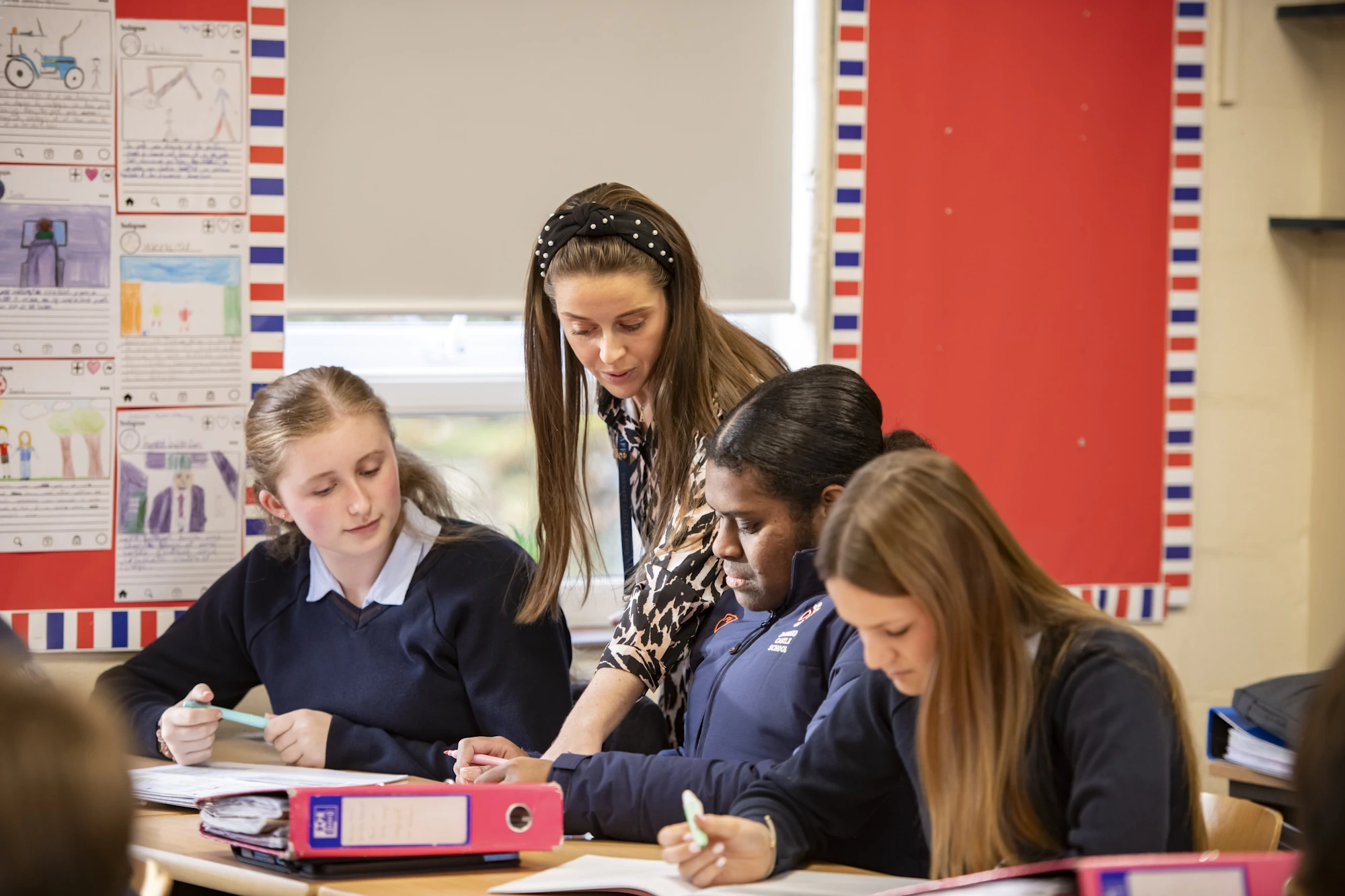 A Barnard Castle School teacher speaking to three students in the classroom.