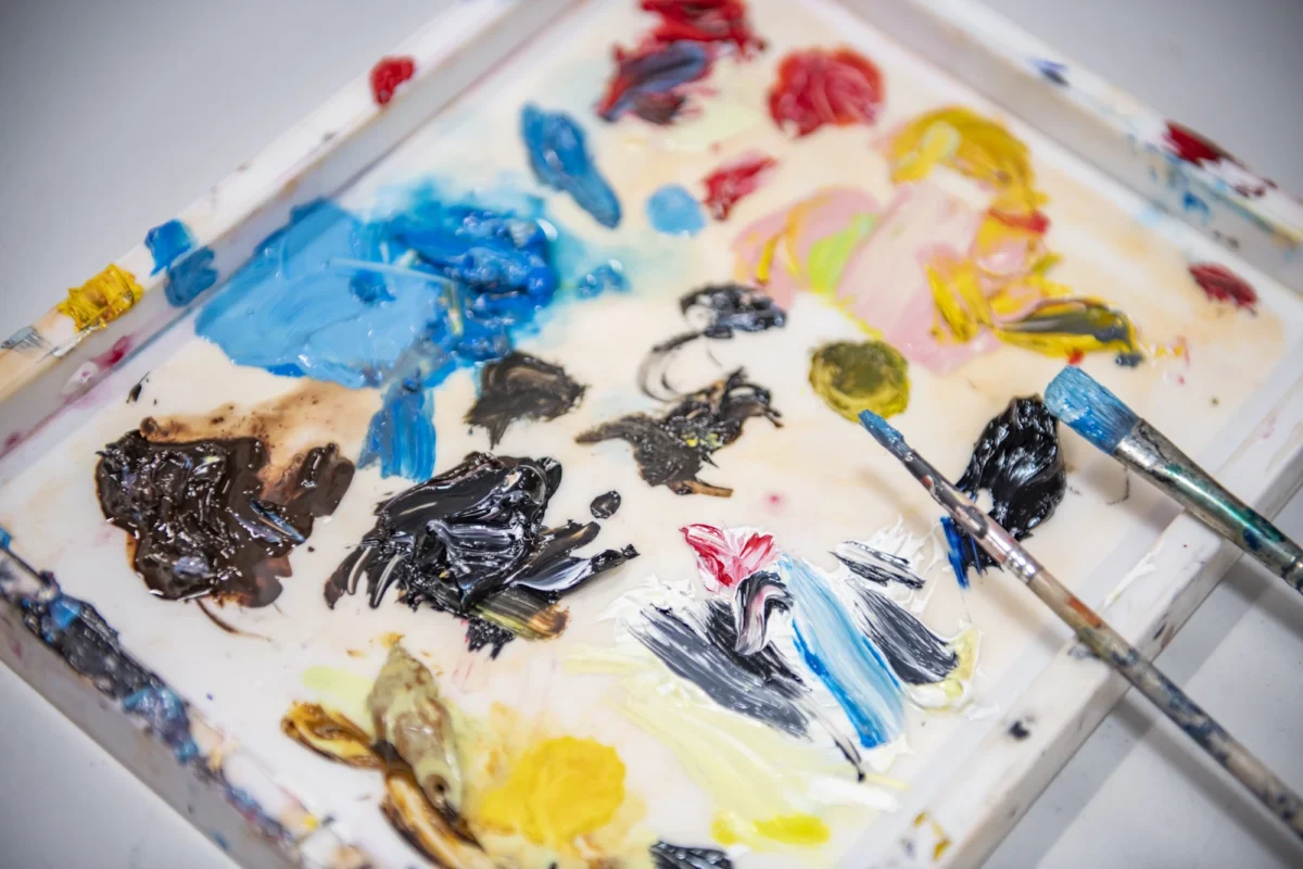 A palette with various paint colors and brushes arranged on it, ready for artistic use.