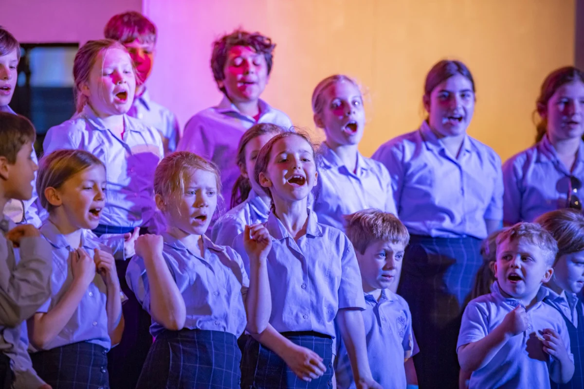 A group of Barnard Castle School pupils on stage singing.