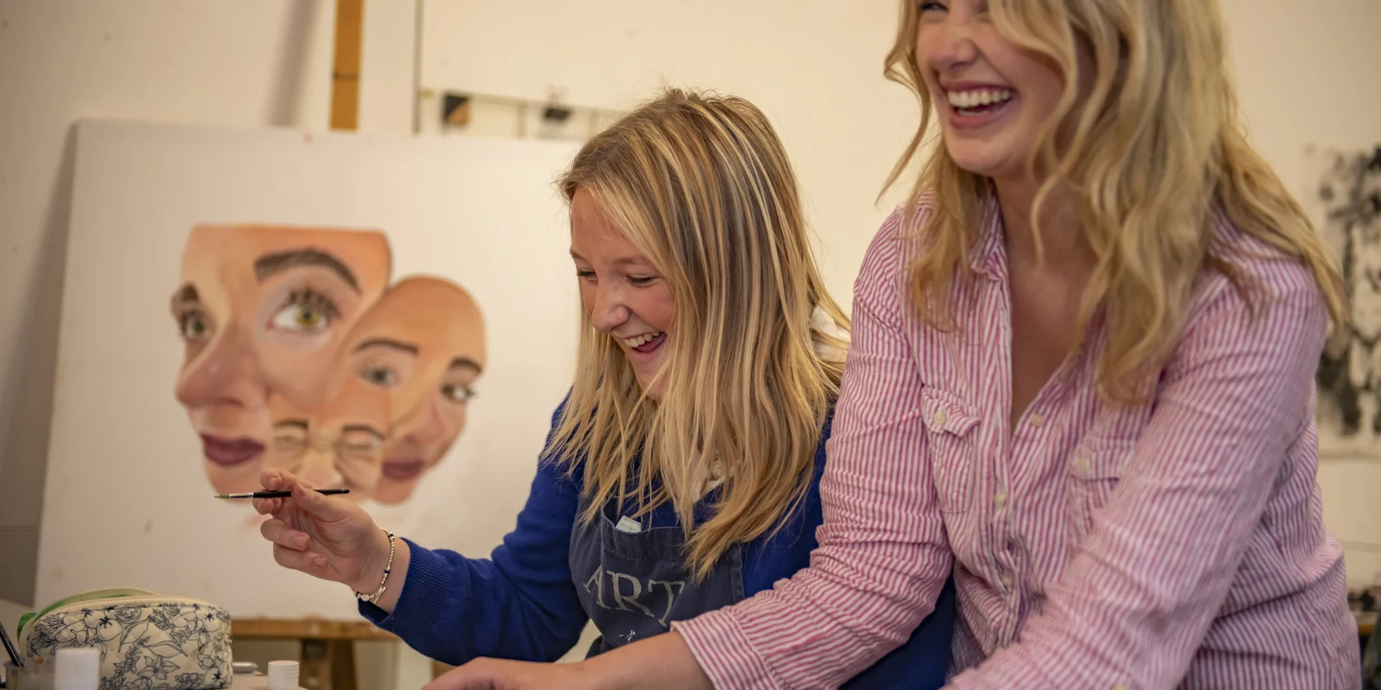 Two Barnard Castle School pupils in an art room laughing.