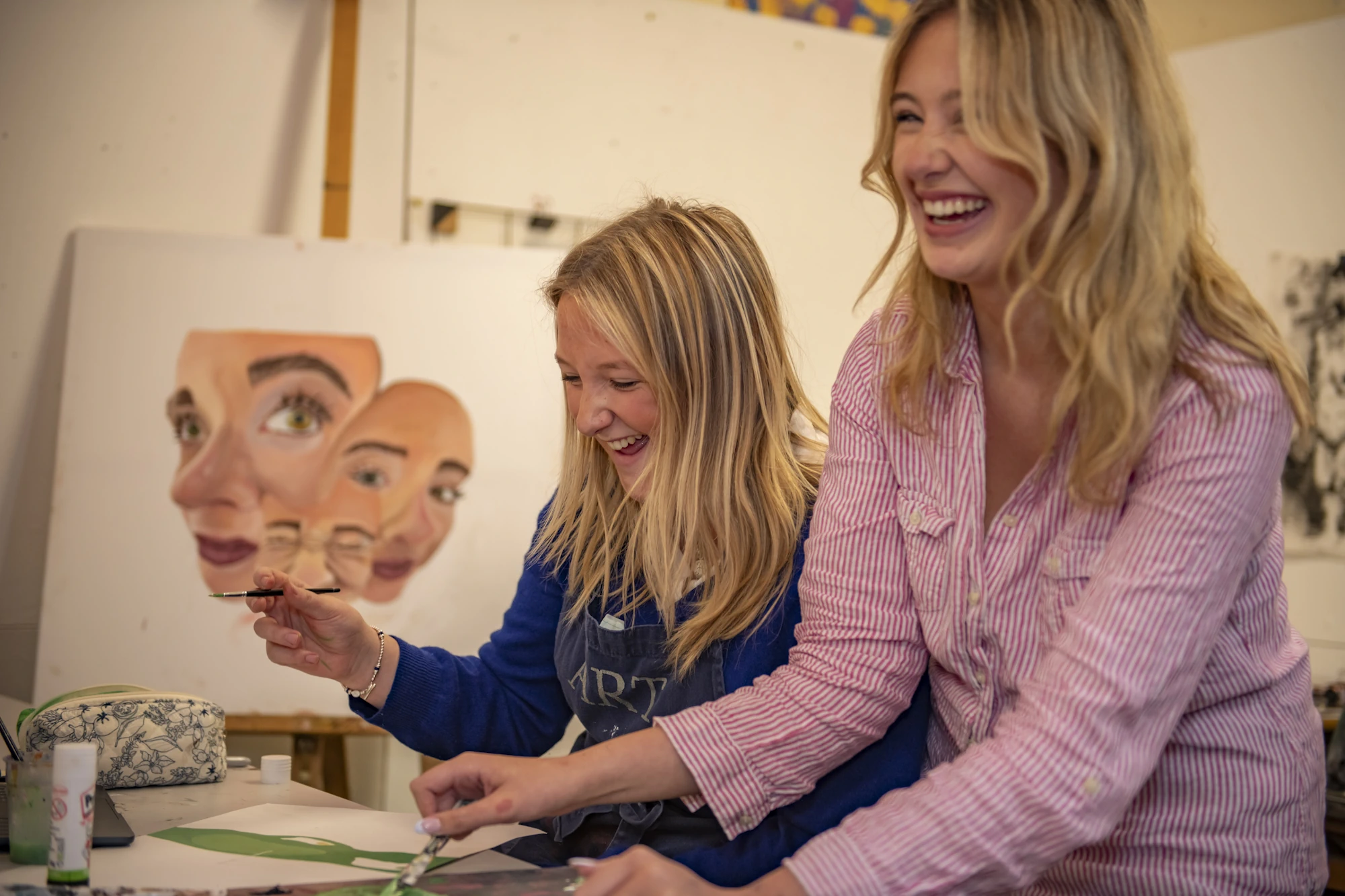 Two Barnard Castle School pupils in an art room laughing.