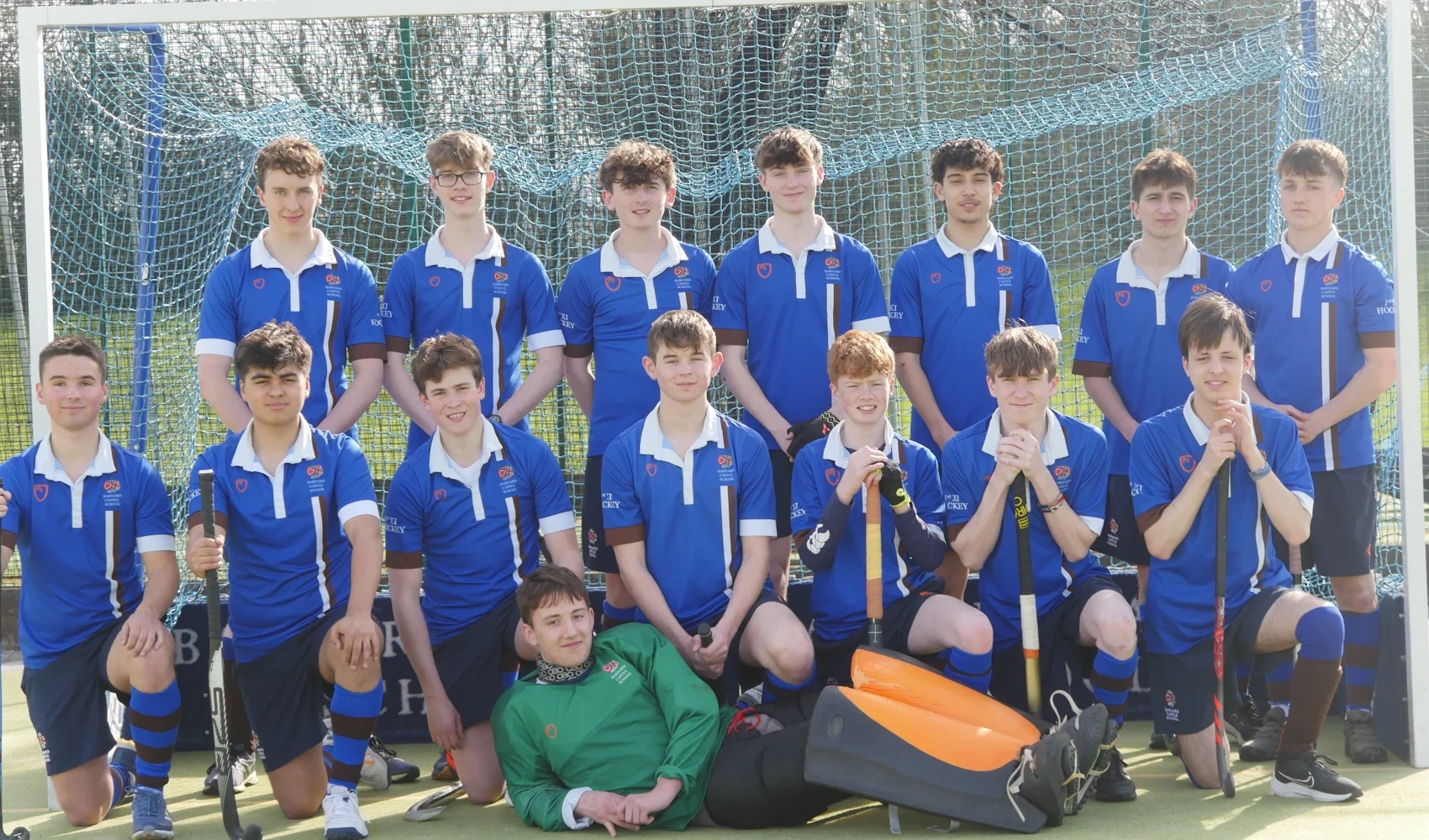 Hockey boys team stood in front of goal.