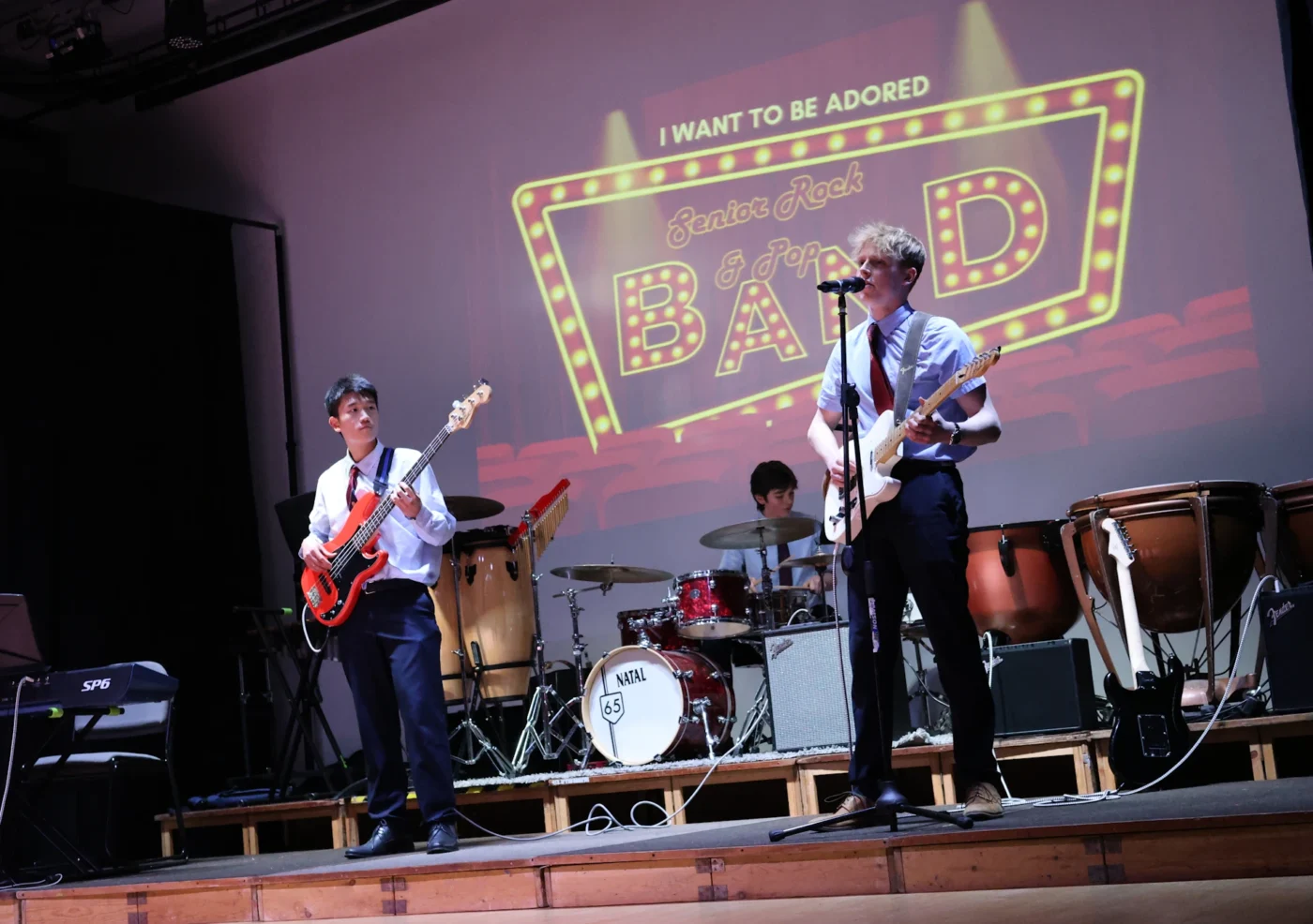 Barnard Castle School pupils performing with guitars, bass, drums and a mic.