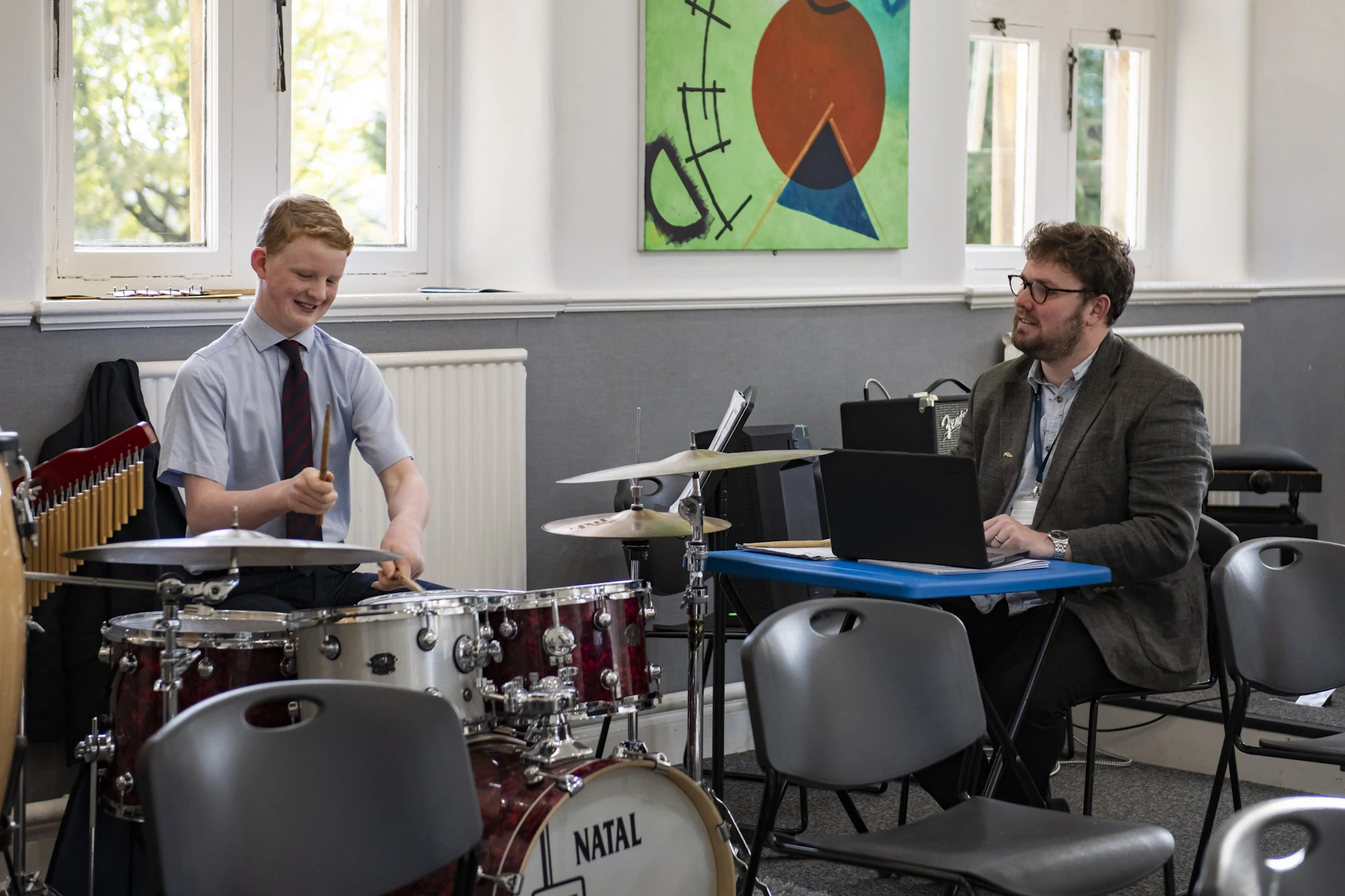 Barnard Castle School pupil playing the drums with a teacher watching.