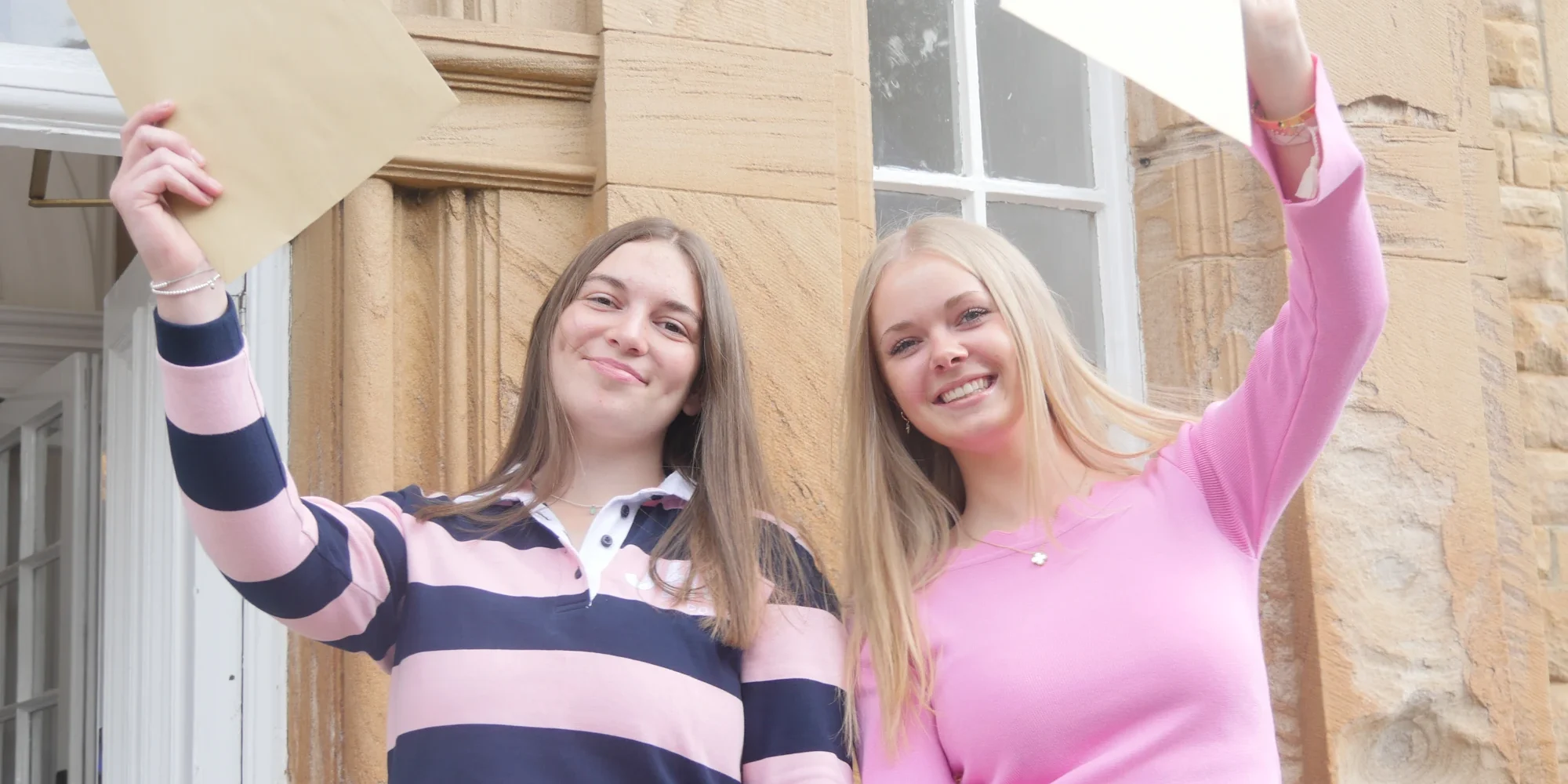 Two sixth form students holding their results.