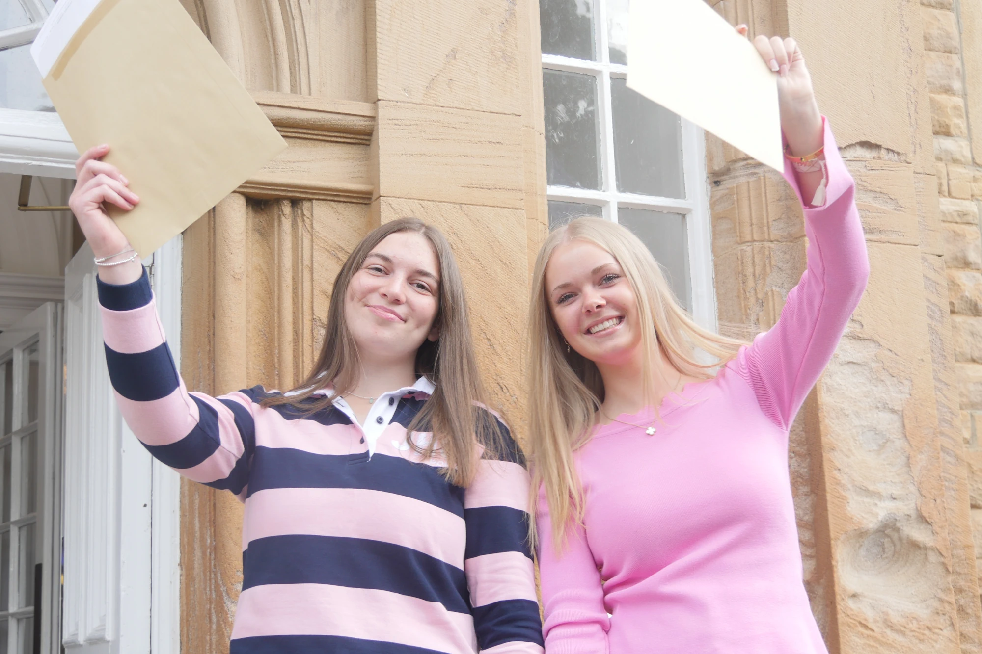 Two sixth form students holding their results.