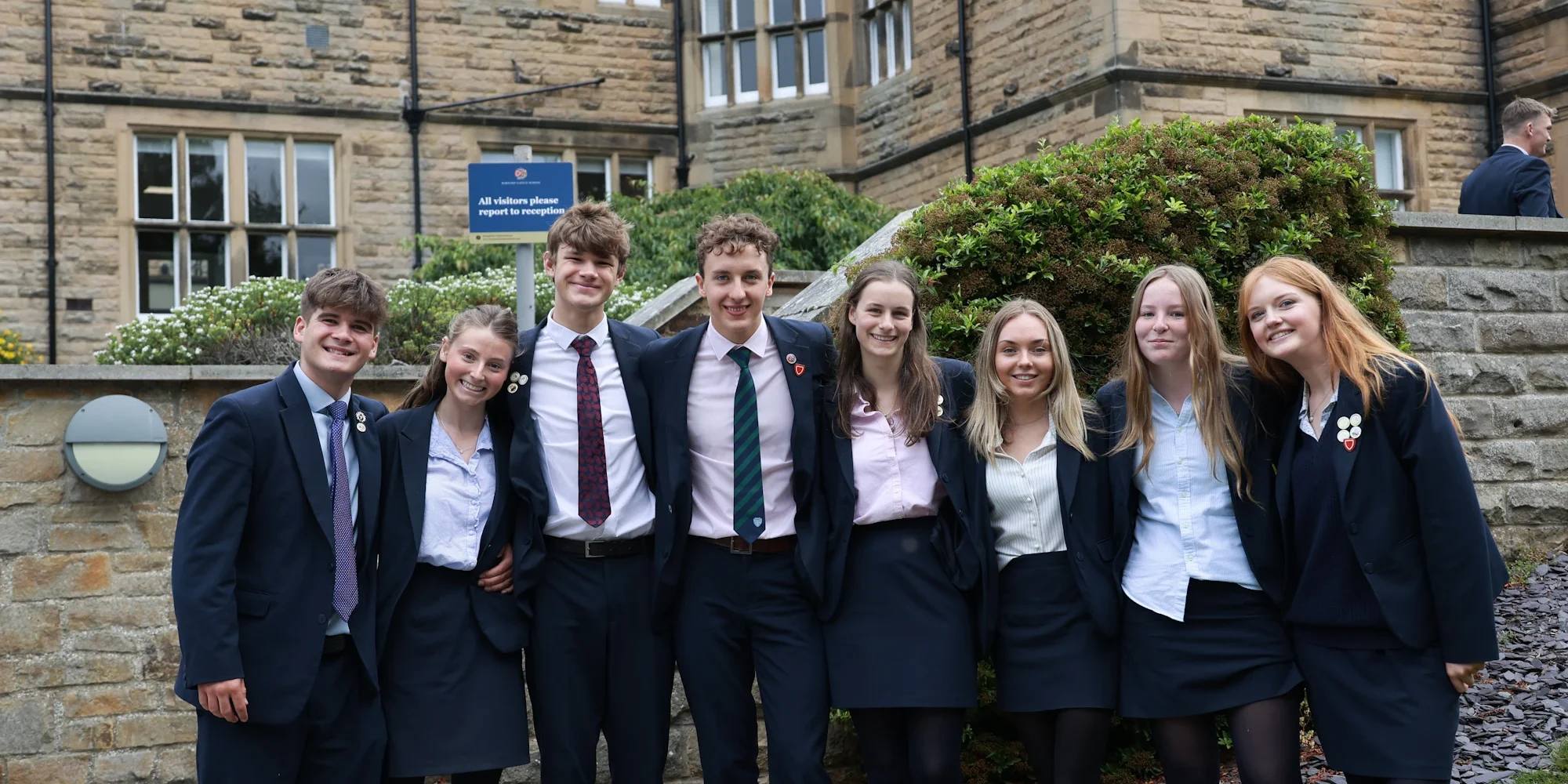 A group of students standing outside the front of the school building.