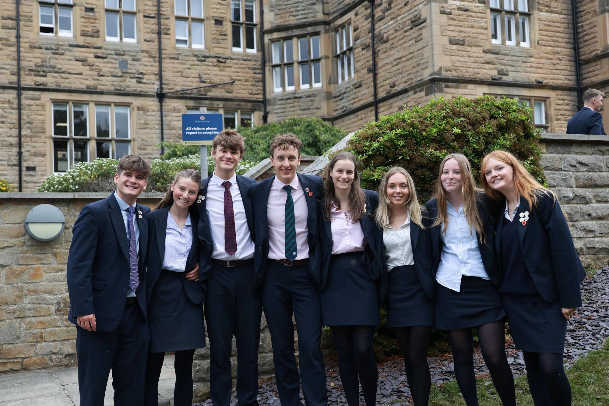 A group of students standing outside the front of the school building.