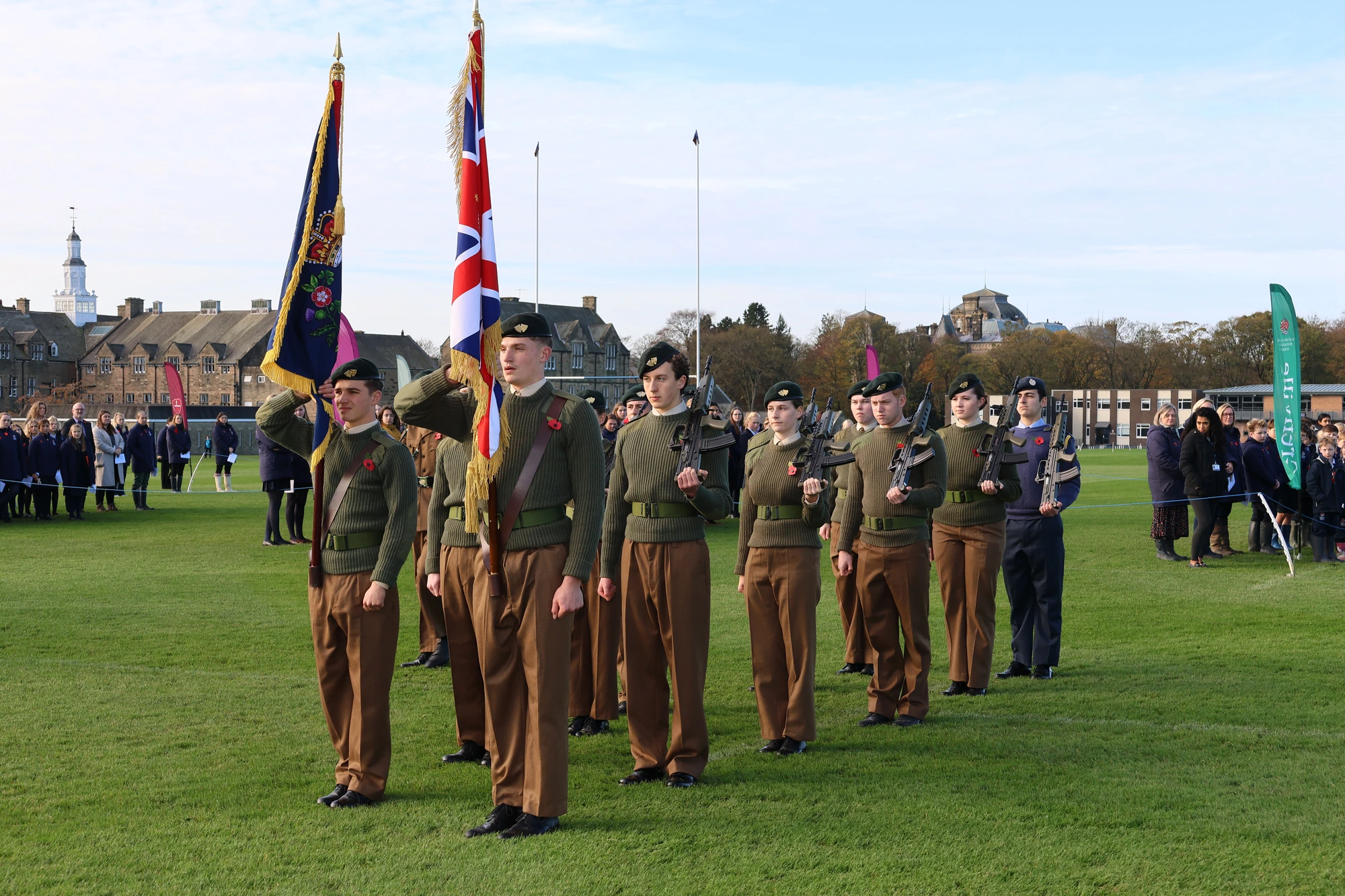 Cadets in uniform holding flags on playing field.