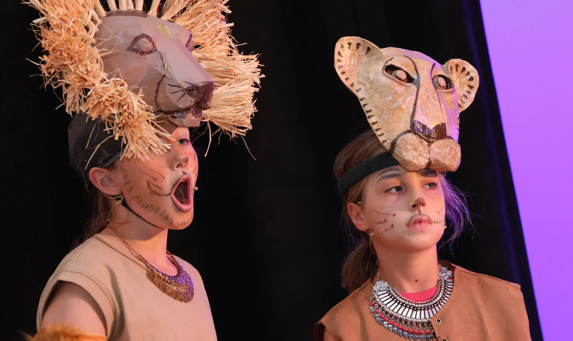 Two girls on stage dressed as lions and singing.