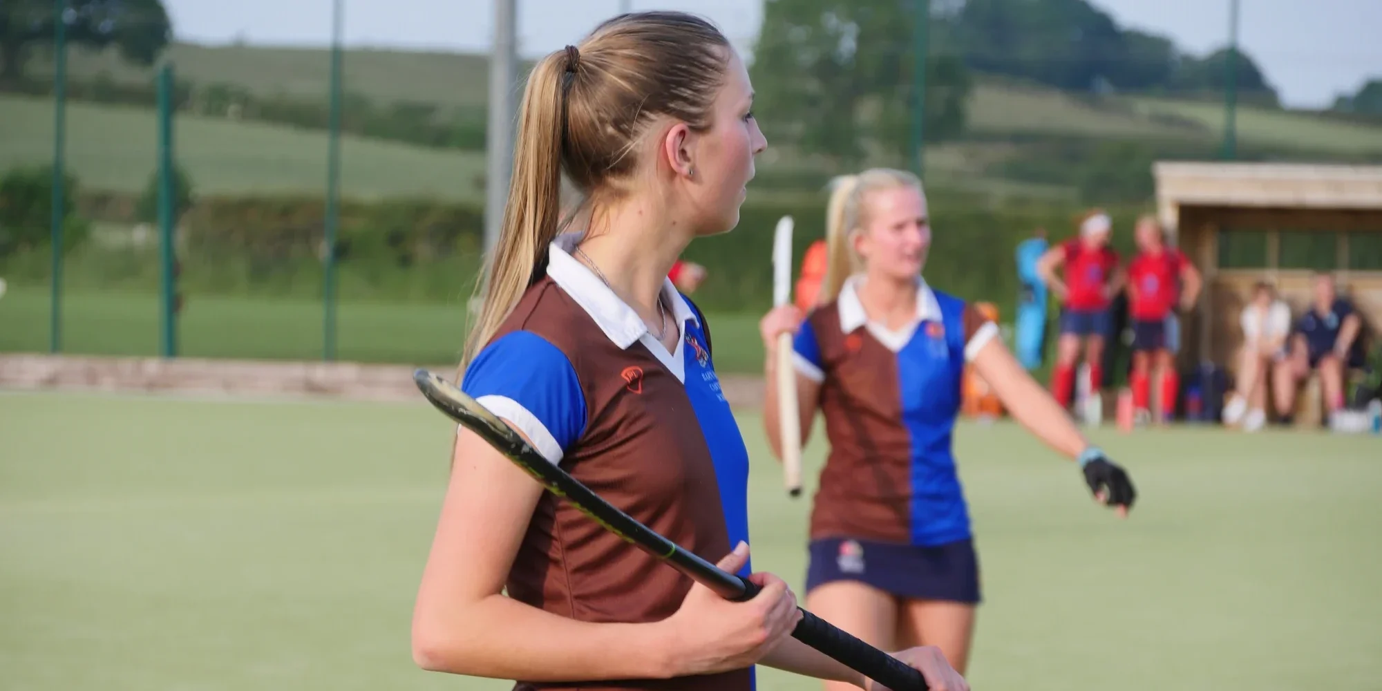 Two female hockey players on a field.
