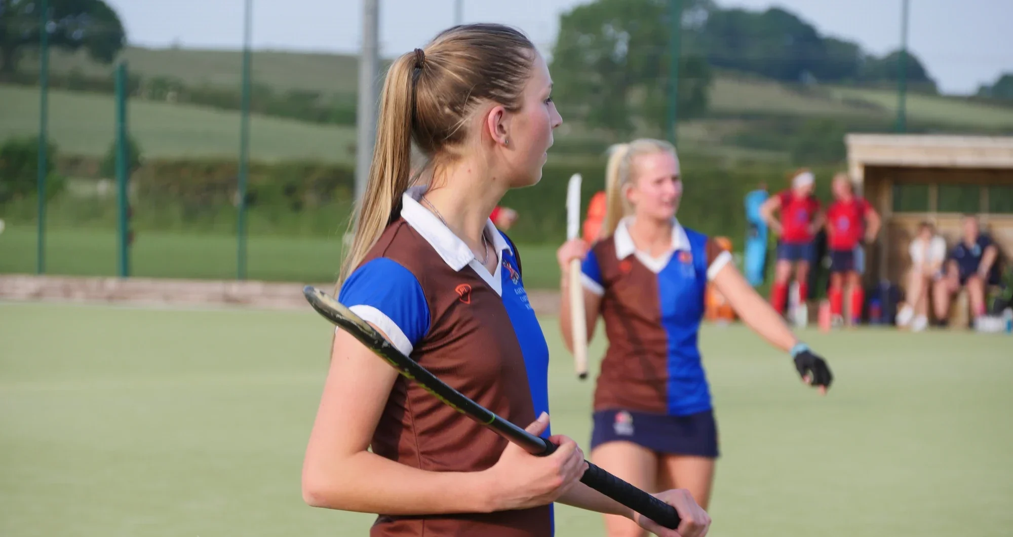 Two female hockey players on a field.