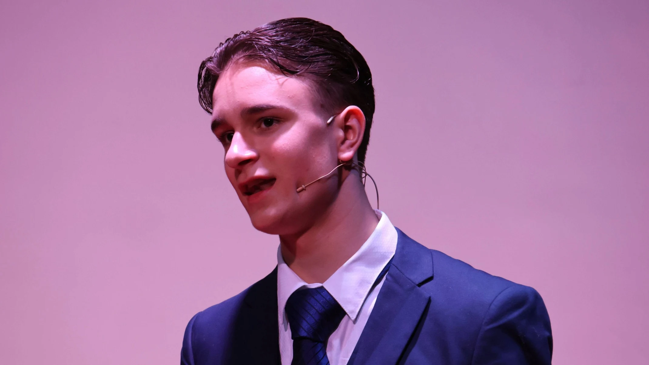A Barney student in a blue suit singing.