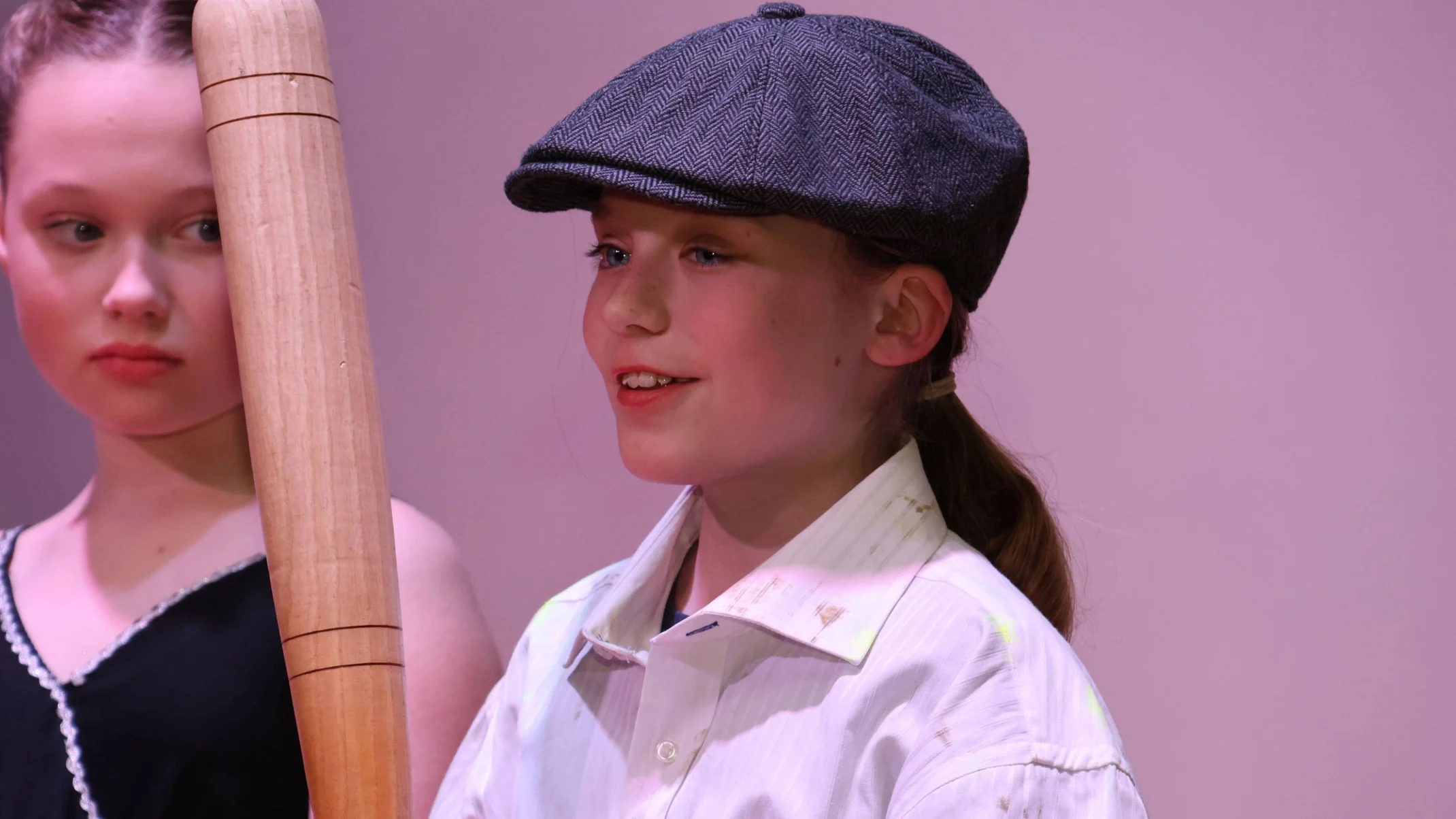 A student wearing a flat cap wielding a baseball bat.