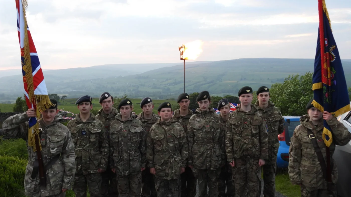 CCF cadets standing together in front of a lit beacon.