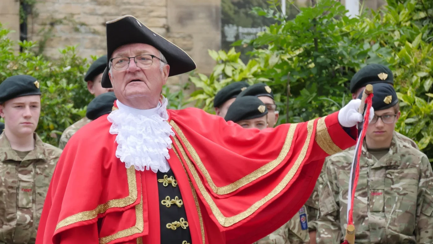 A Town Crier in full attire in front of CCF cadets.