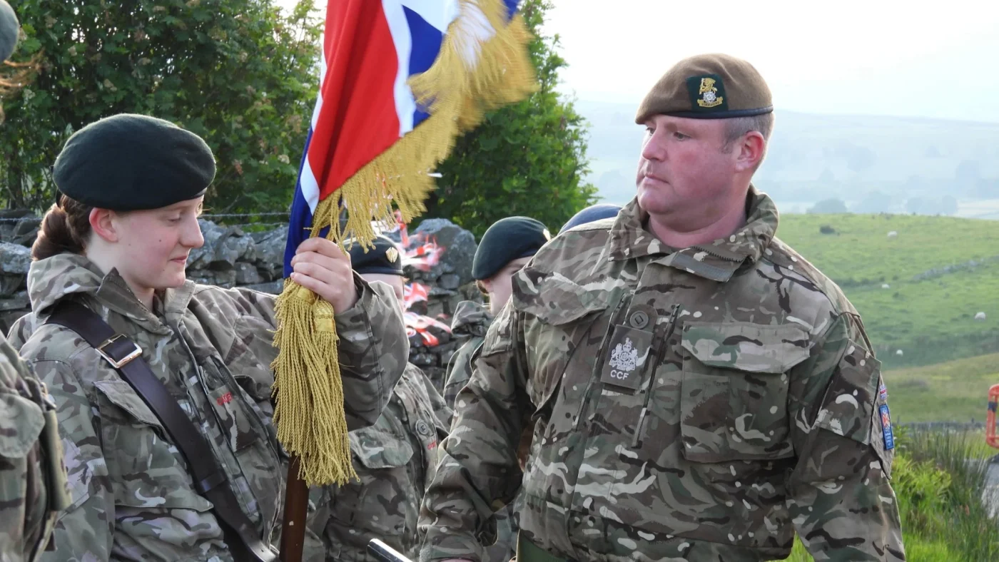 People in military uniform carrying flags and marching.