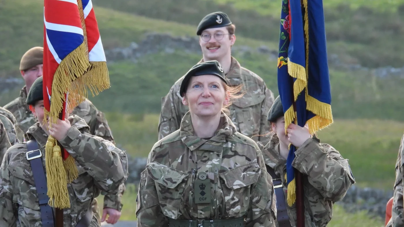 People of various ages in military uniform holding flags.