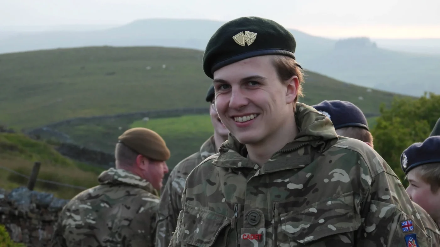 A young man in military unform smiling.