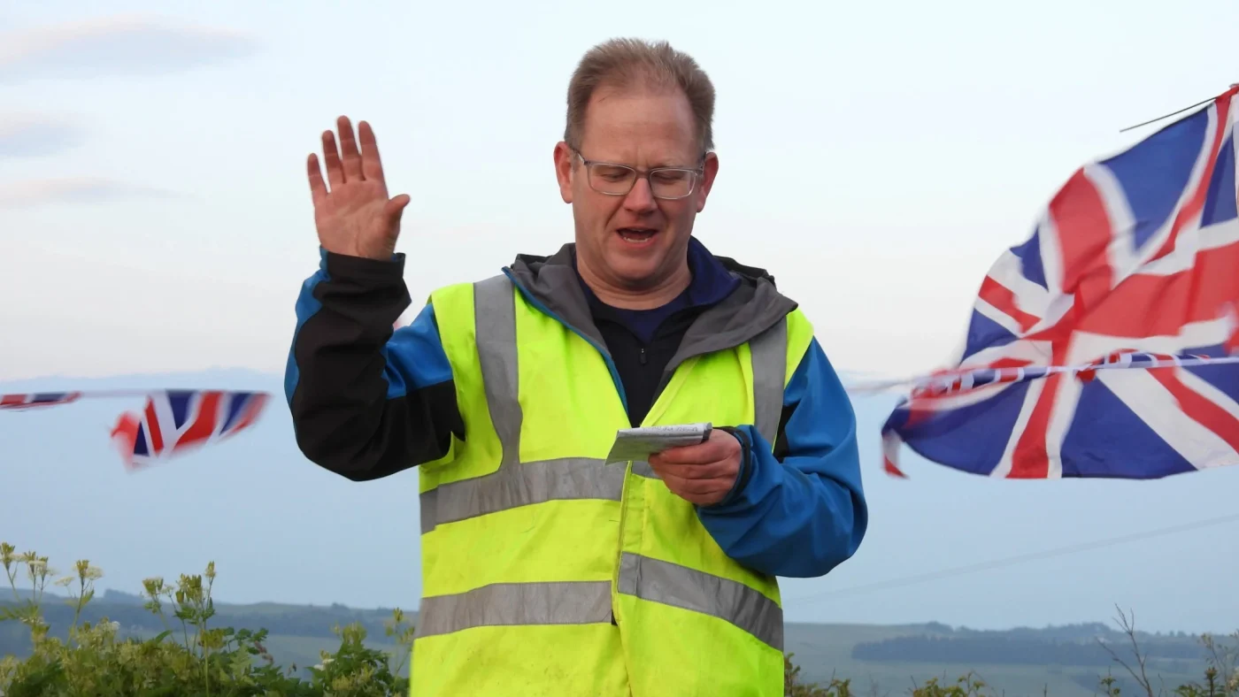 A man in a hi-vis jacket delivering a speech.