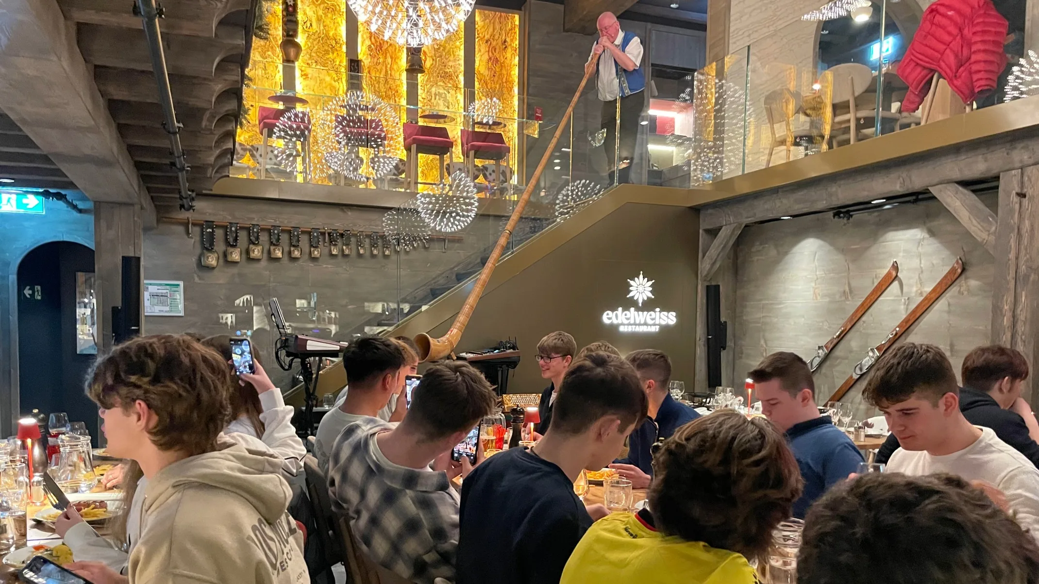 Barney students eat in a food hall as a plan plays a long wood instrument.