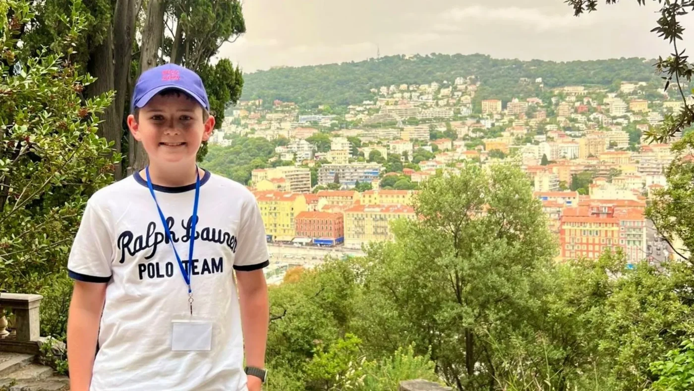 A Barney student stands in front of a French city.