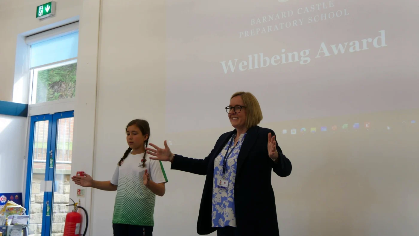 A woman and young girl in front of a projection of the words 'Wellbeing Award'.