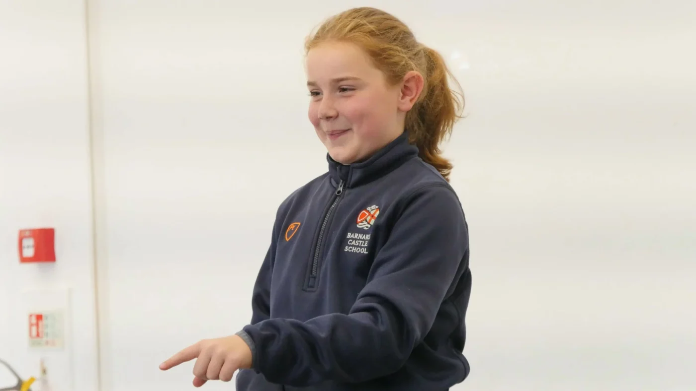 A Barney prep school student pointing and smiling.