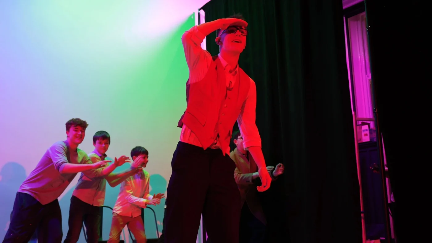 Four Barney students performing in multi-coloured light.