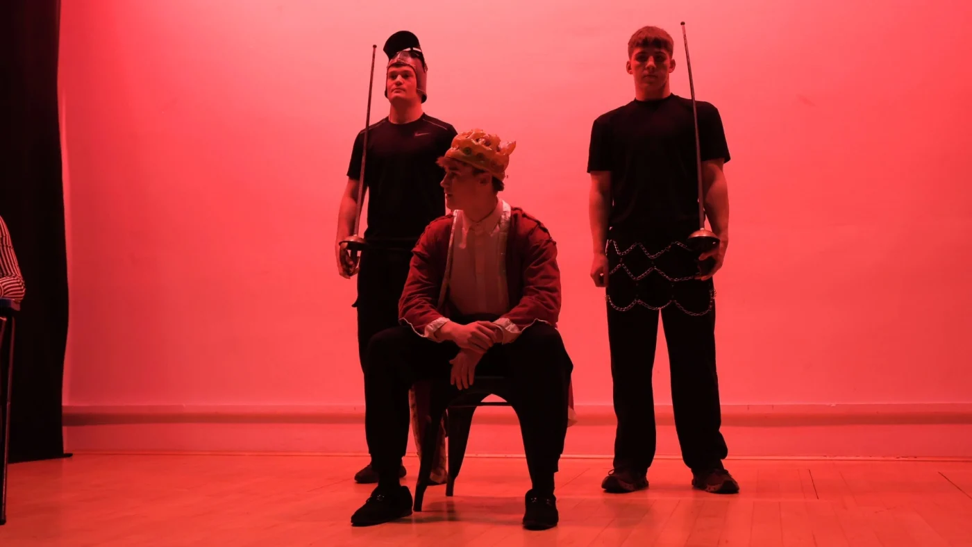 Josh from York House plays a king, sitting in red light.