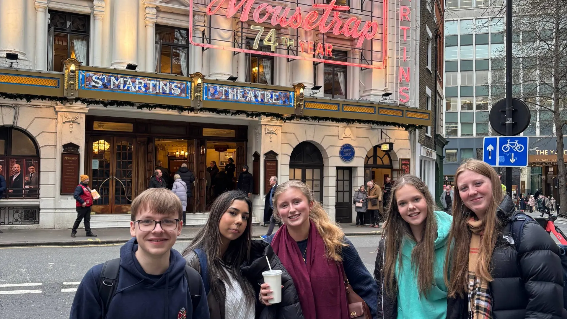 Barney theatre students next to a neon-lit sign for Agatha Christie's The Mousetrap.