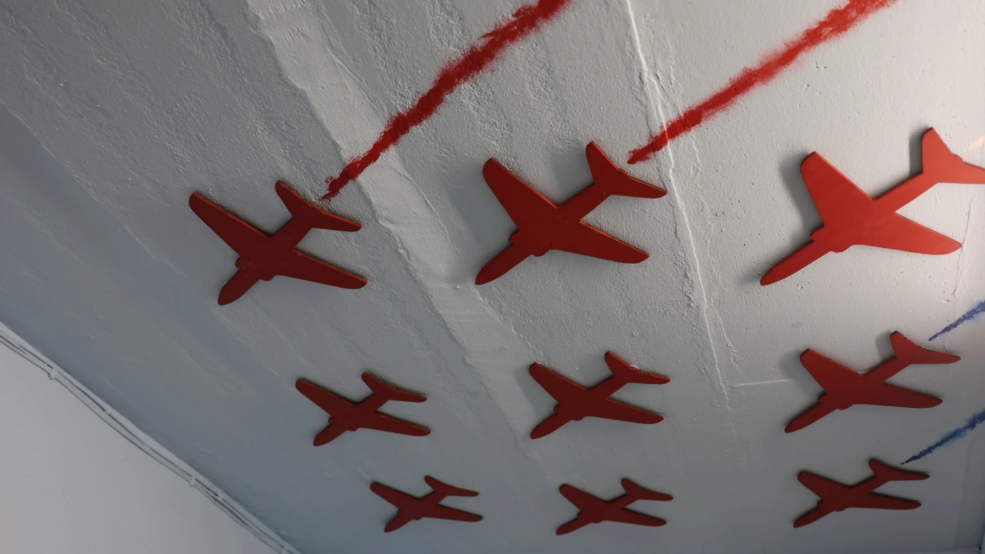 A ceiling display featuring red planes trailing across it.