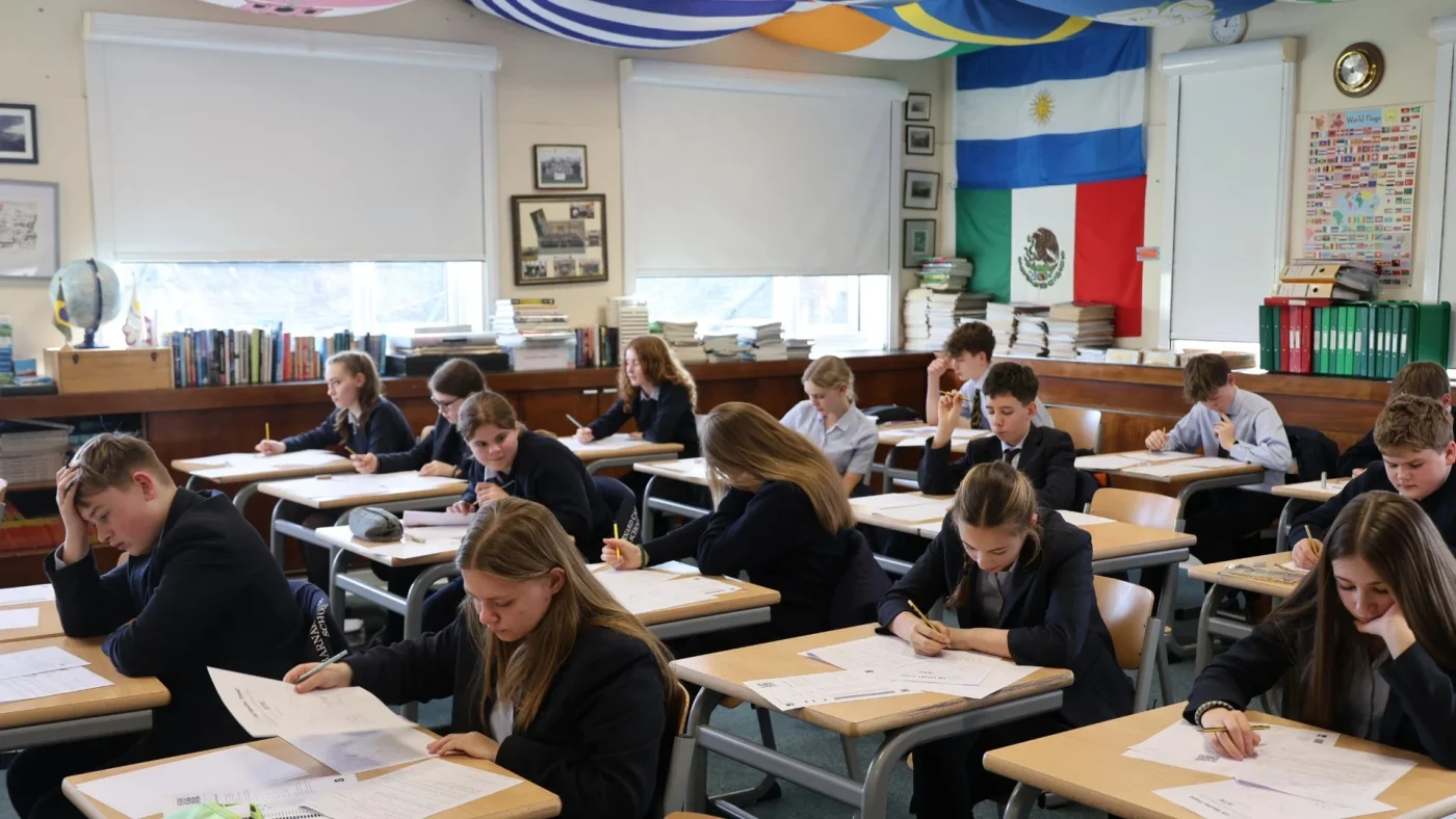 Students writing at desks during the UKMT Intermediate Maths Challenge.