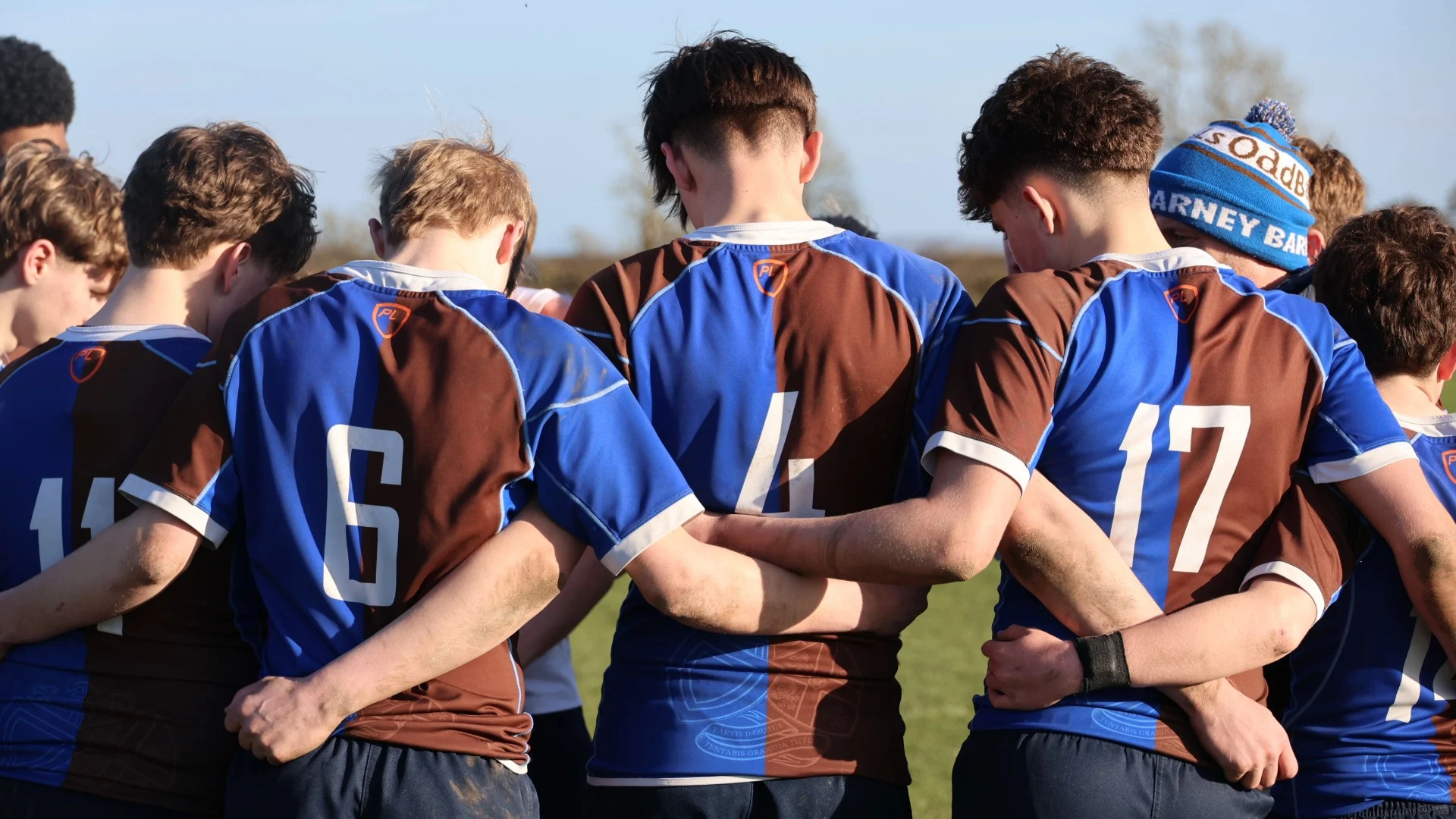 Barney rugby players in a huddle.