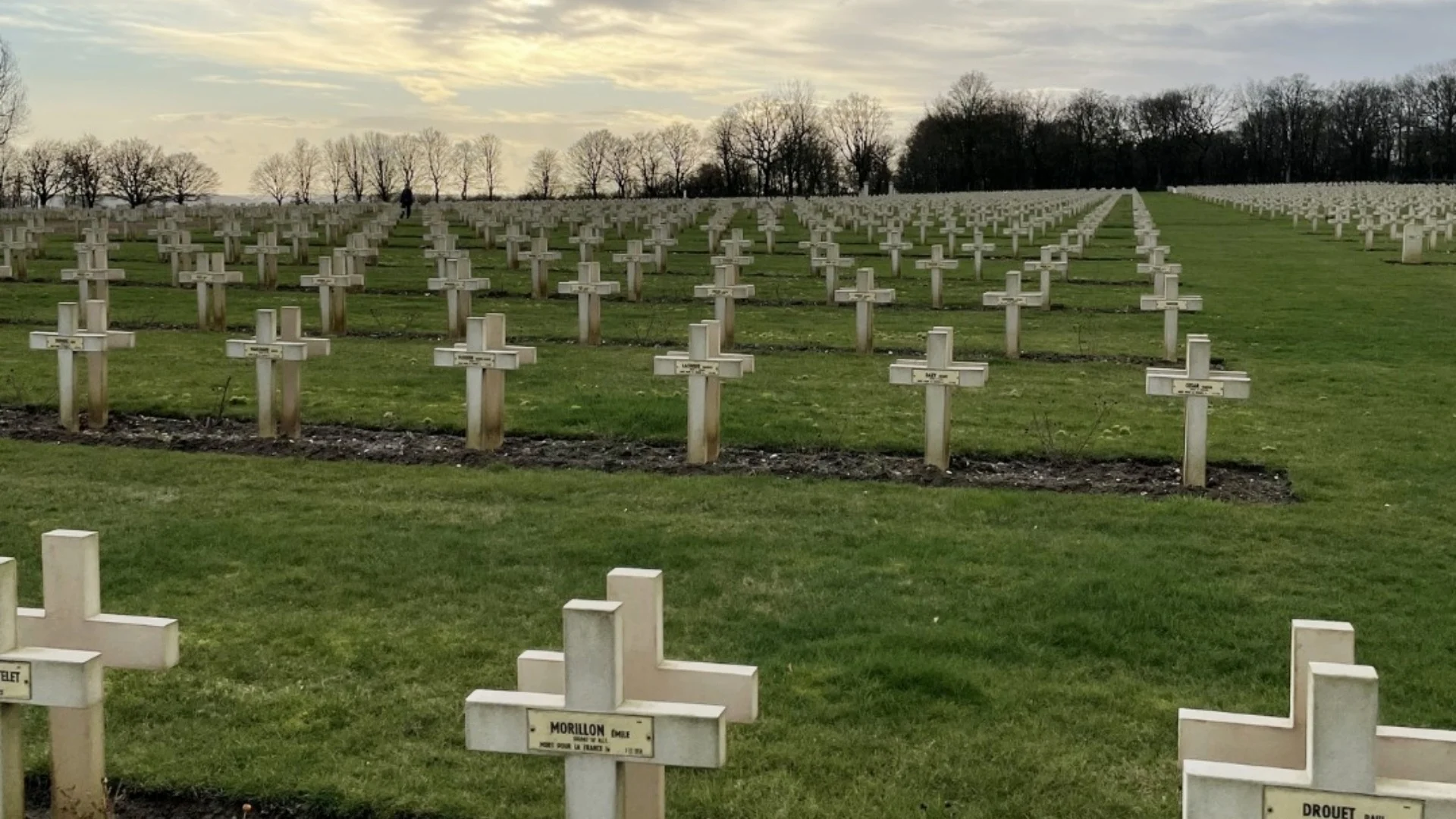 A WW1 cemetery with rows of white crosses stretching out into the distance.
