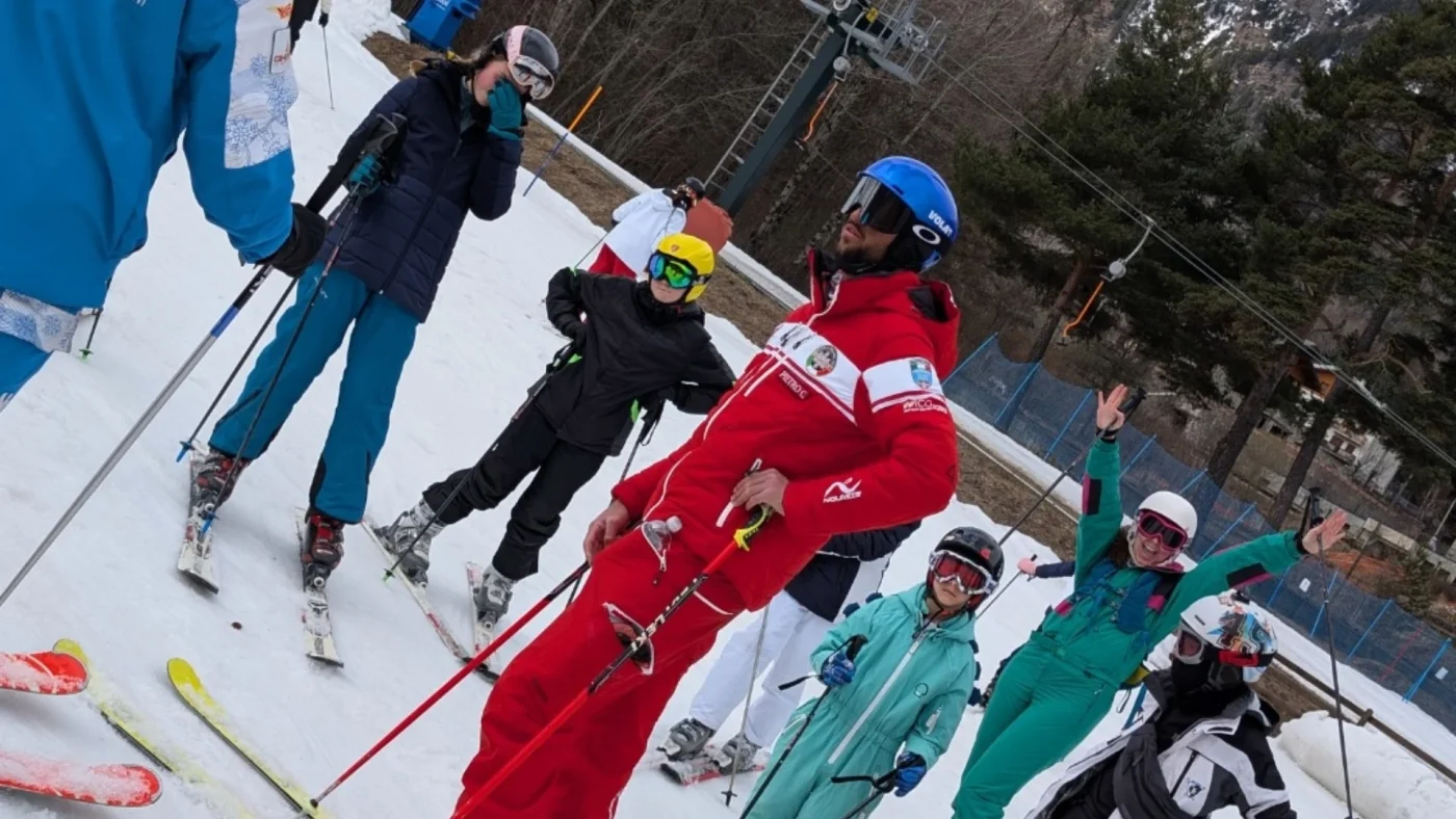 A man in a red ski suit surrounded by students.