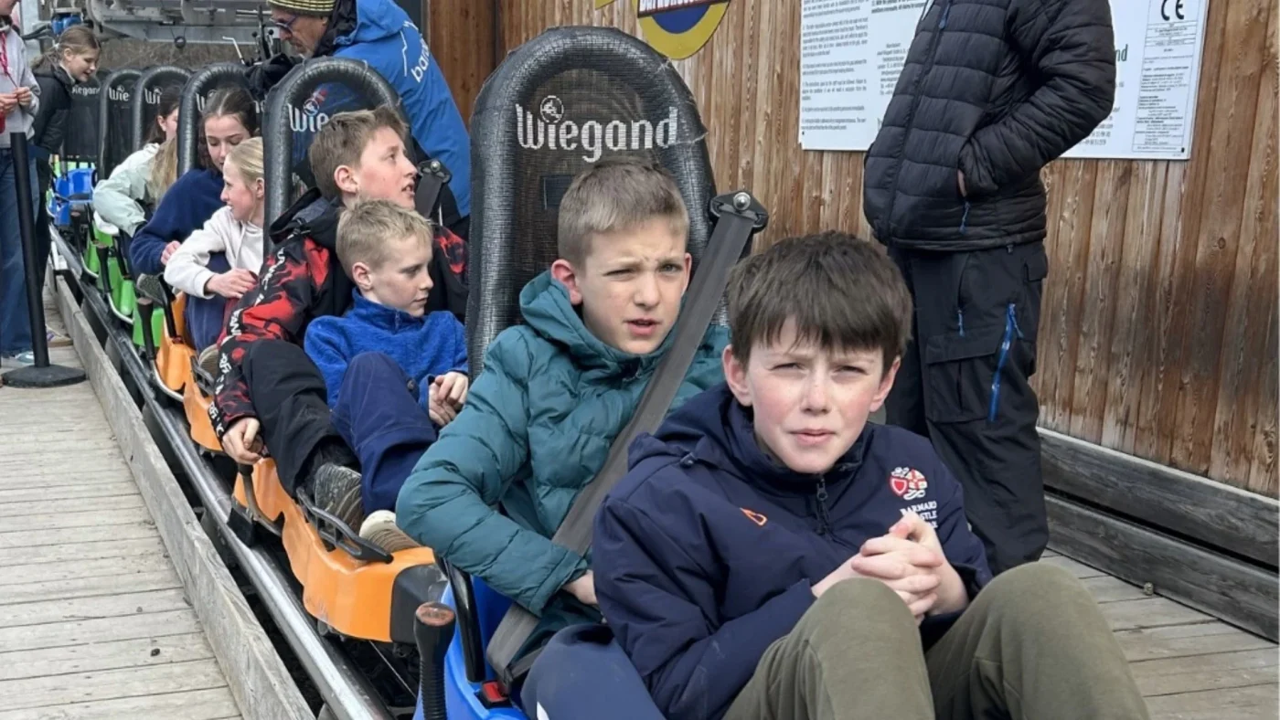 Barney students sit in seats on a ski slope.