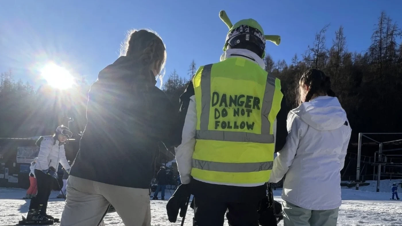 A Barney student dressed like Shrek skiing with friends.