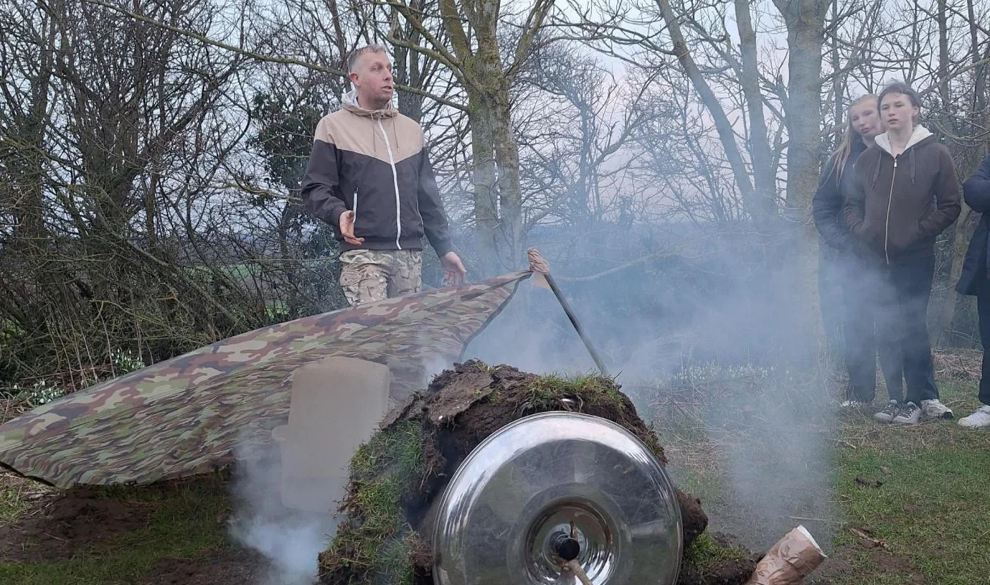Tim, a Barney School chef, demonstrating makeshift pizza oven during Great Tommy Sleep Out.