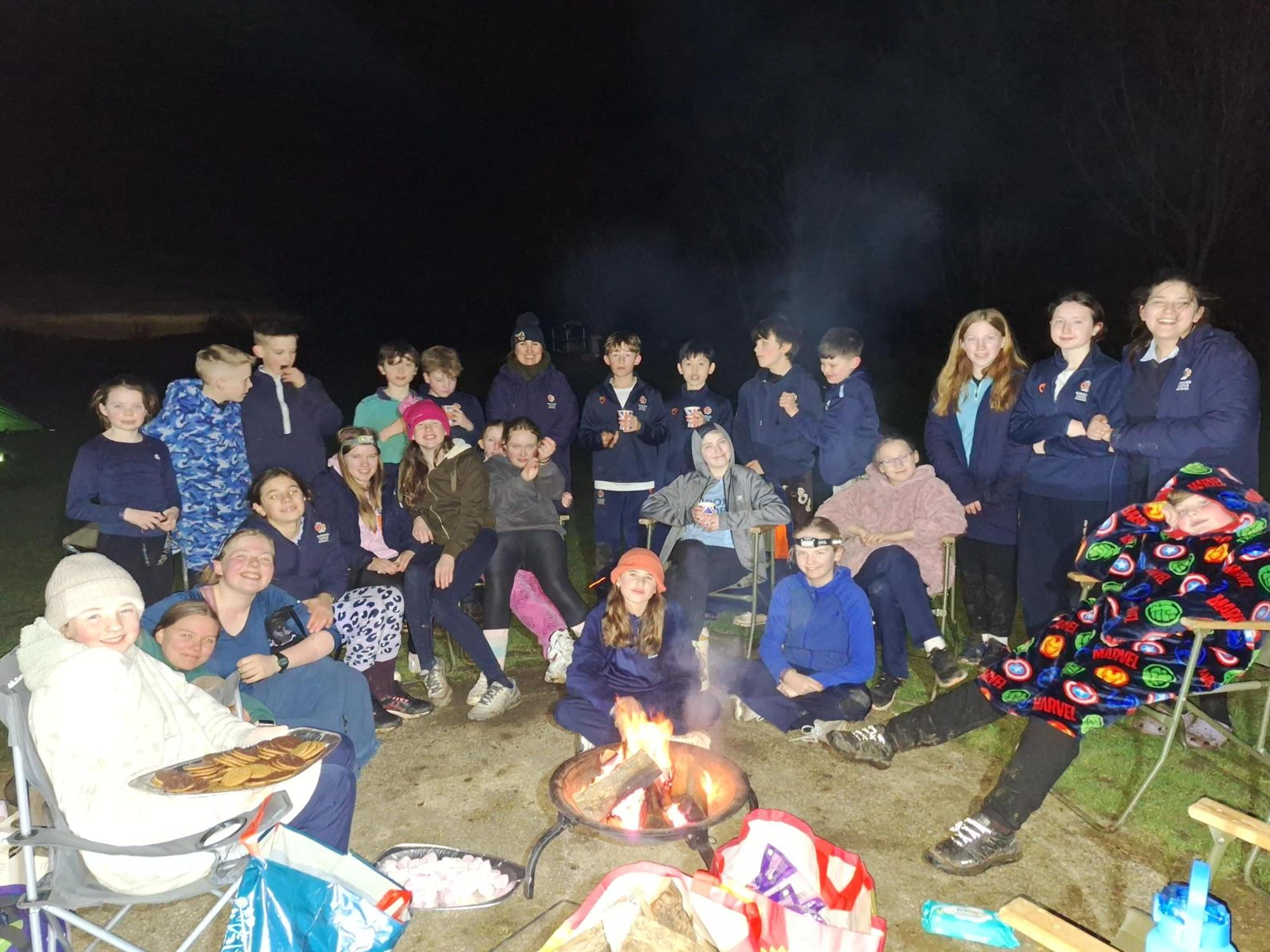 Group photo of pupils around a campfire.