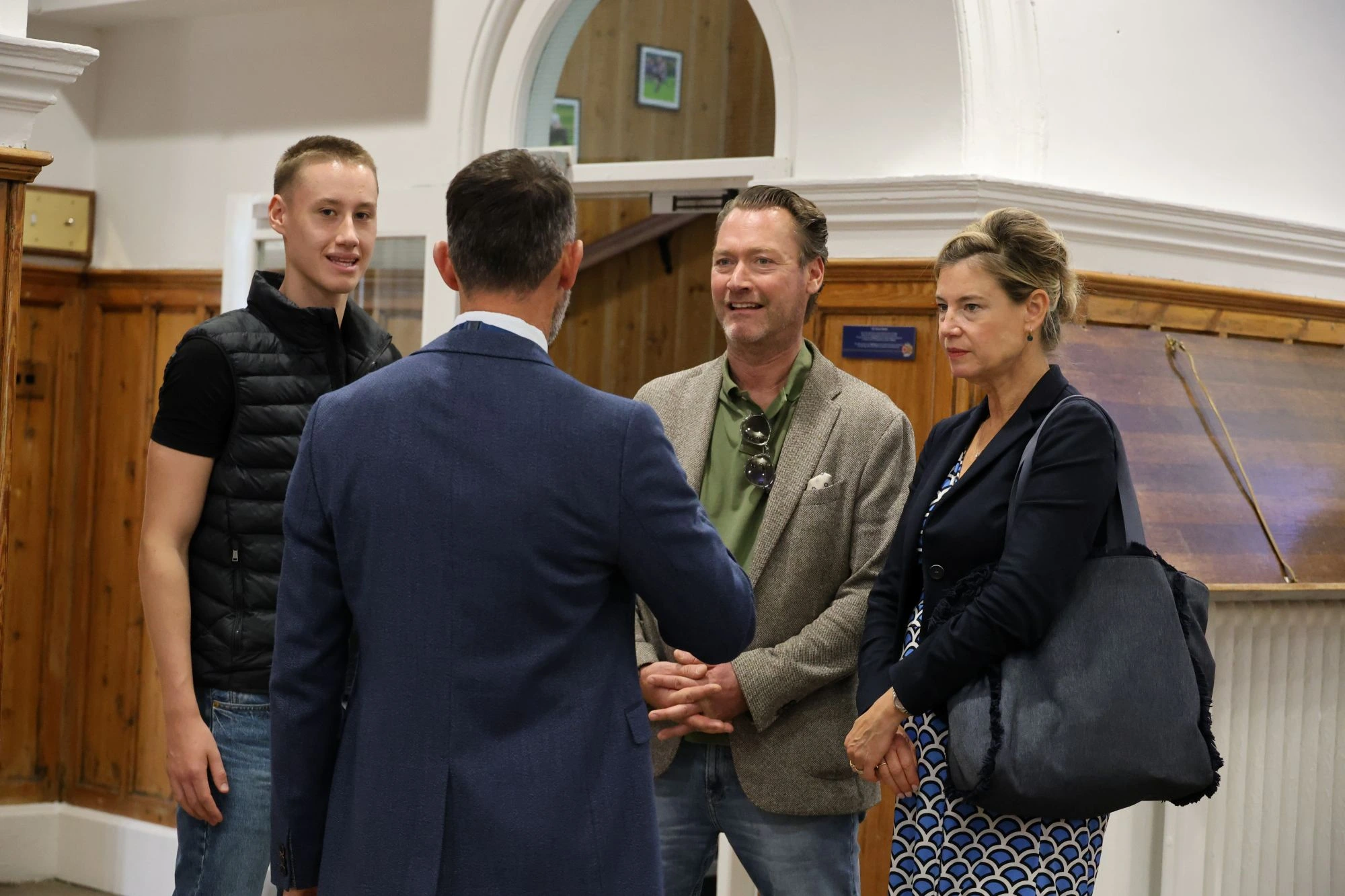 A Barnard Castle staff member in a blue suit greets a student and two adults in a wood-panelled hall.