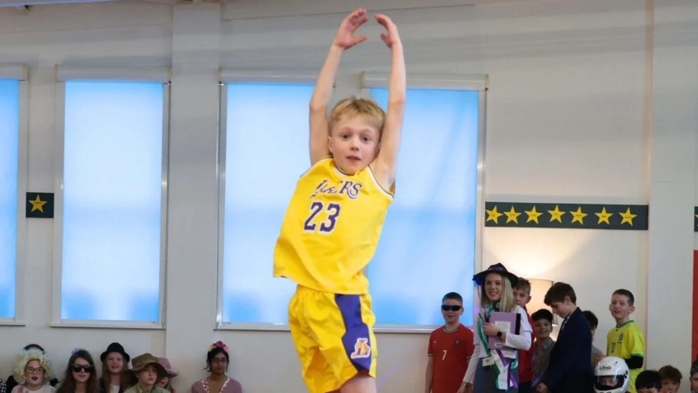A Barney Prep student jumping in a Lakers basketball kit.