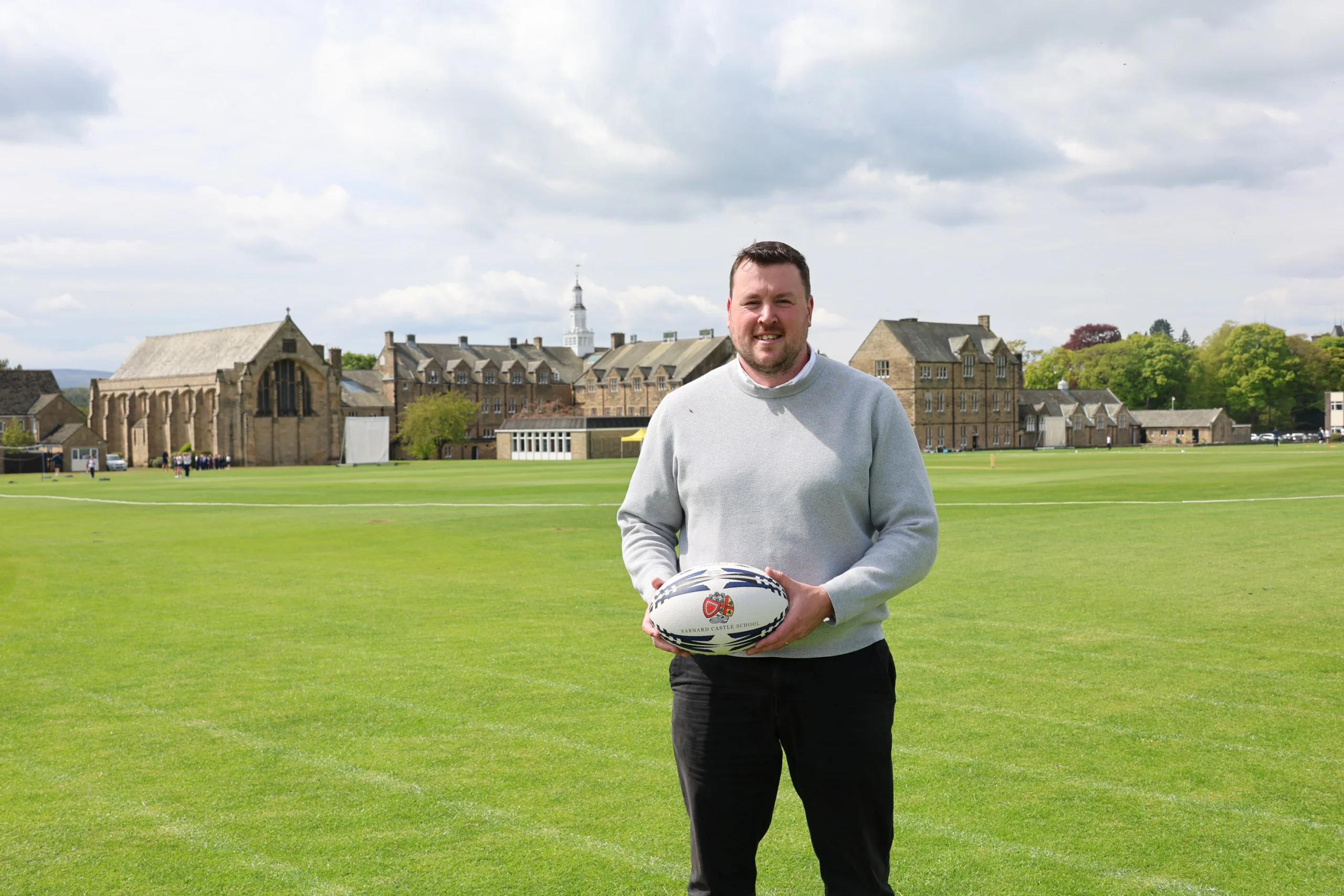 Joe Cain photographed on field holding rugby ball on Barnard Castle School grounds.