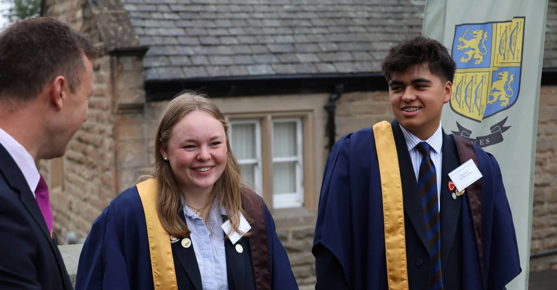 Two international boarders smiling as they talk to a member of staff.