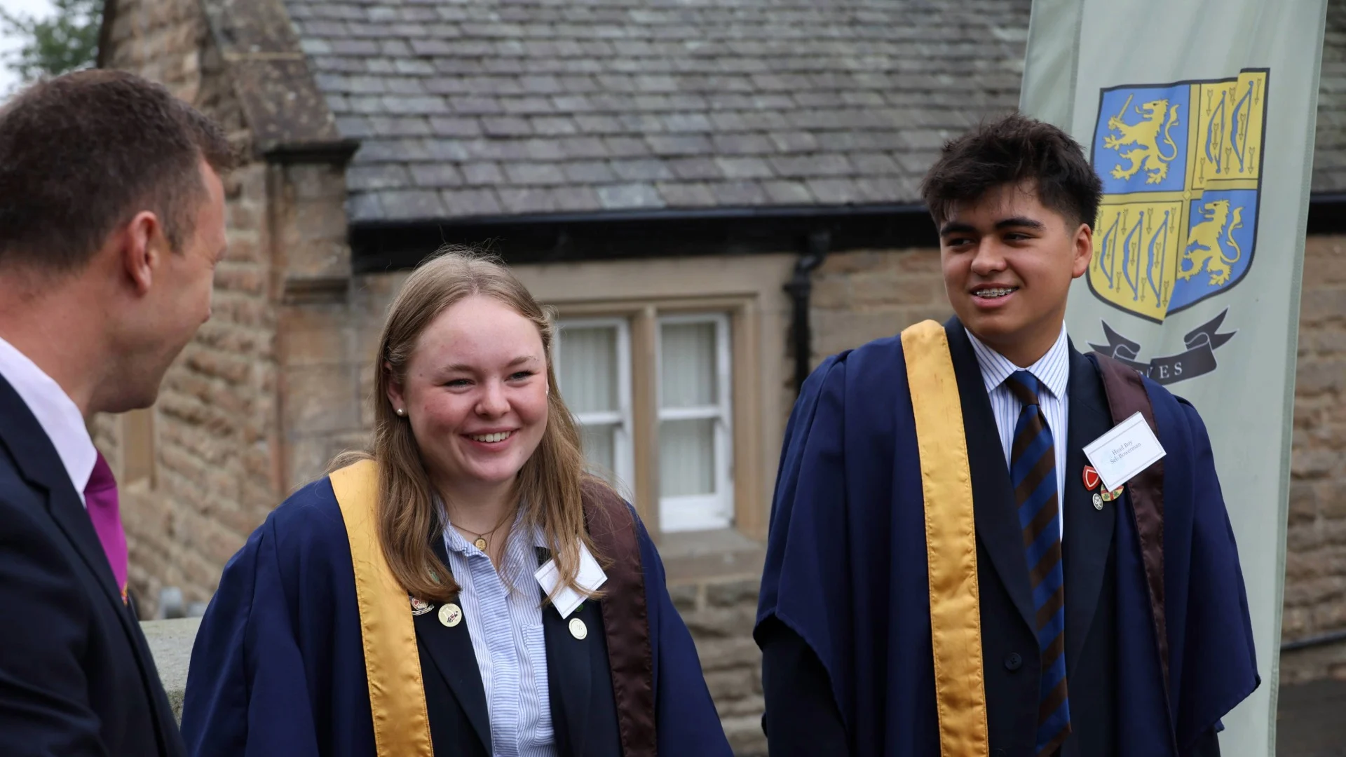 Two international boarders smiling as they talk to a member of staff.