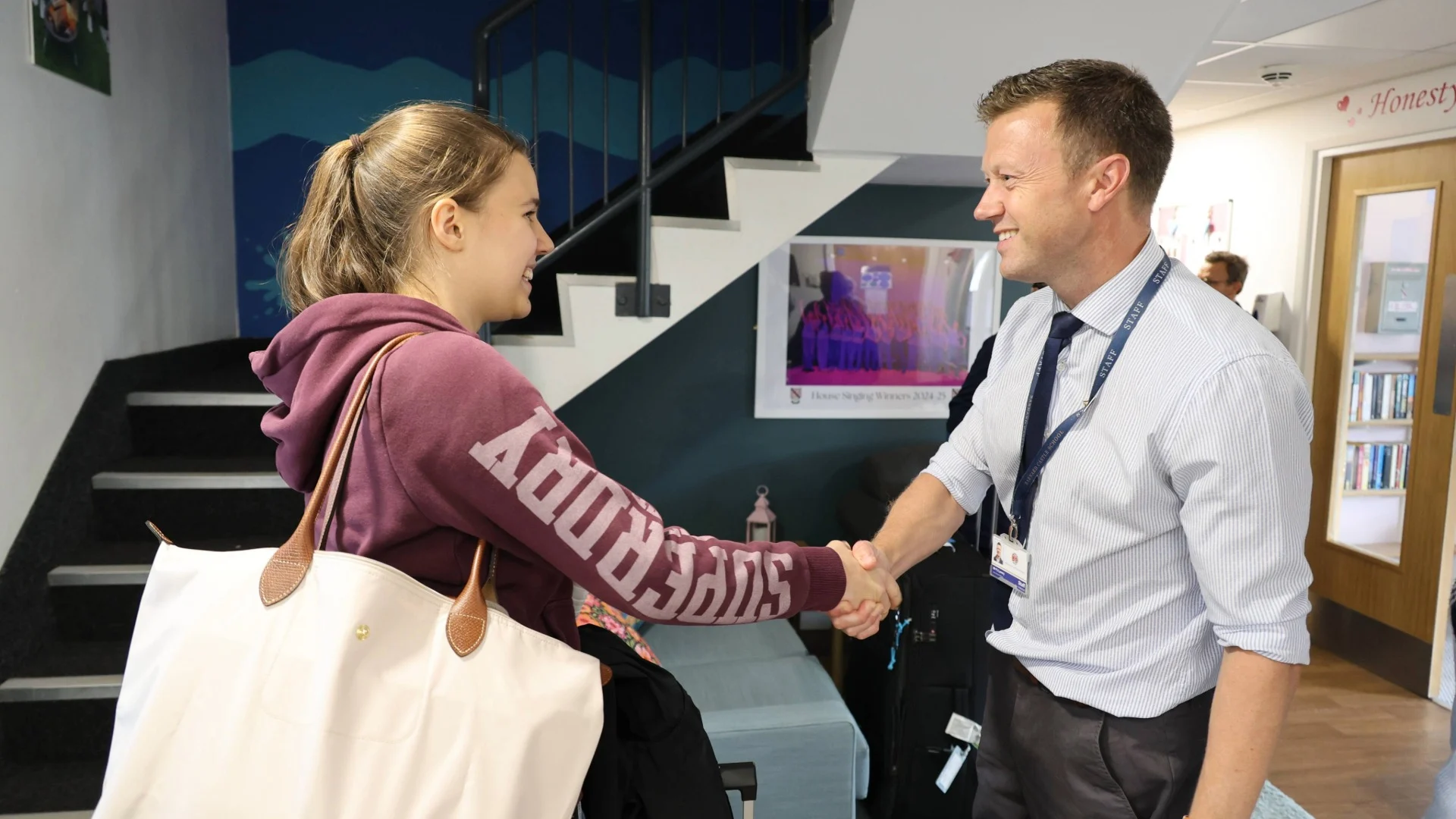An international student shakes hands with a member of staff.