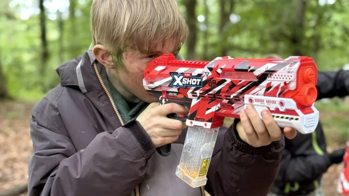 A Year 5 Barney student in the woods with a Nerf gun.