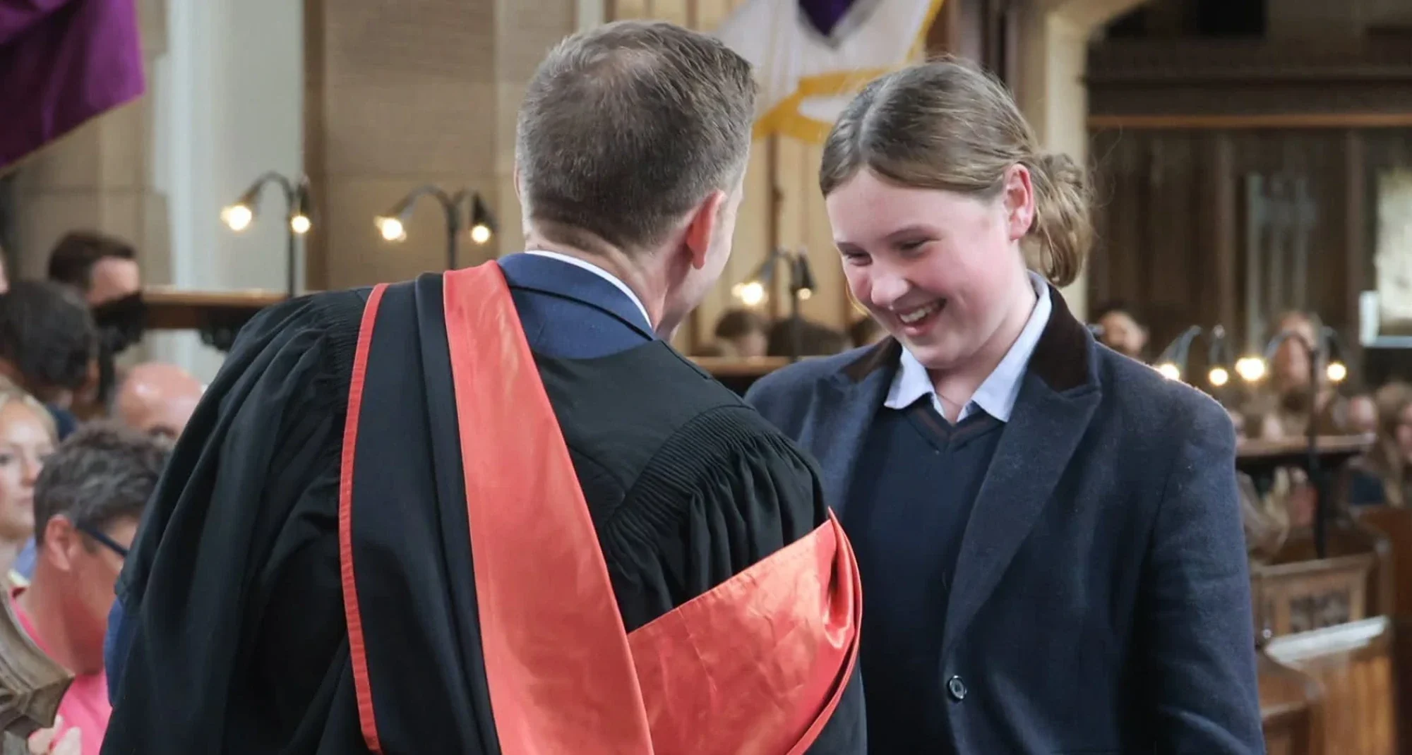 Girl shakes hand with headmaster in prize giving ceremony.