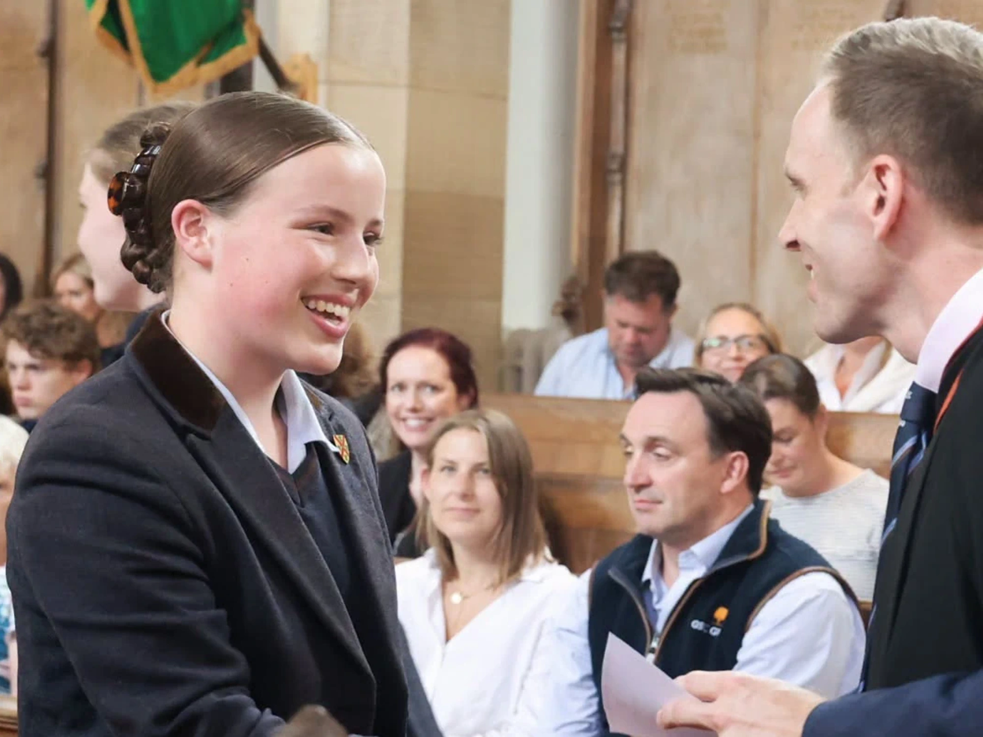 Girl smiling while shaking hands with headmaster.